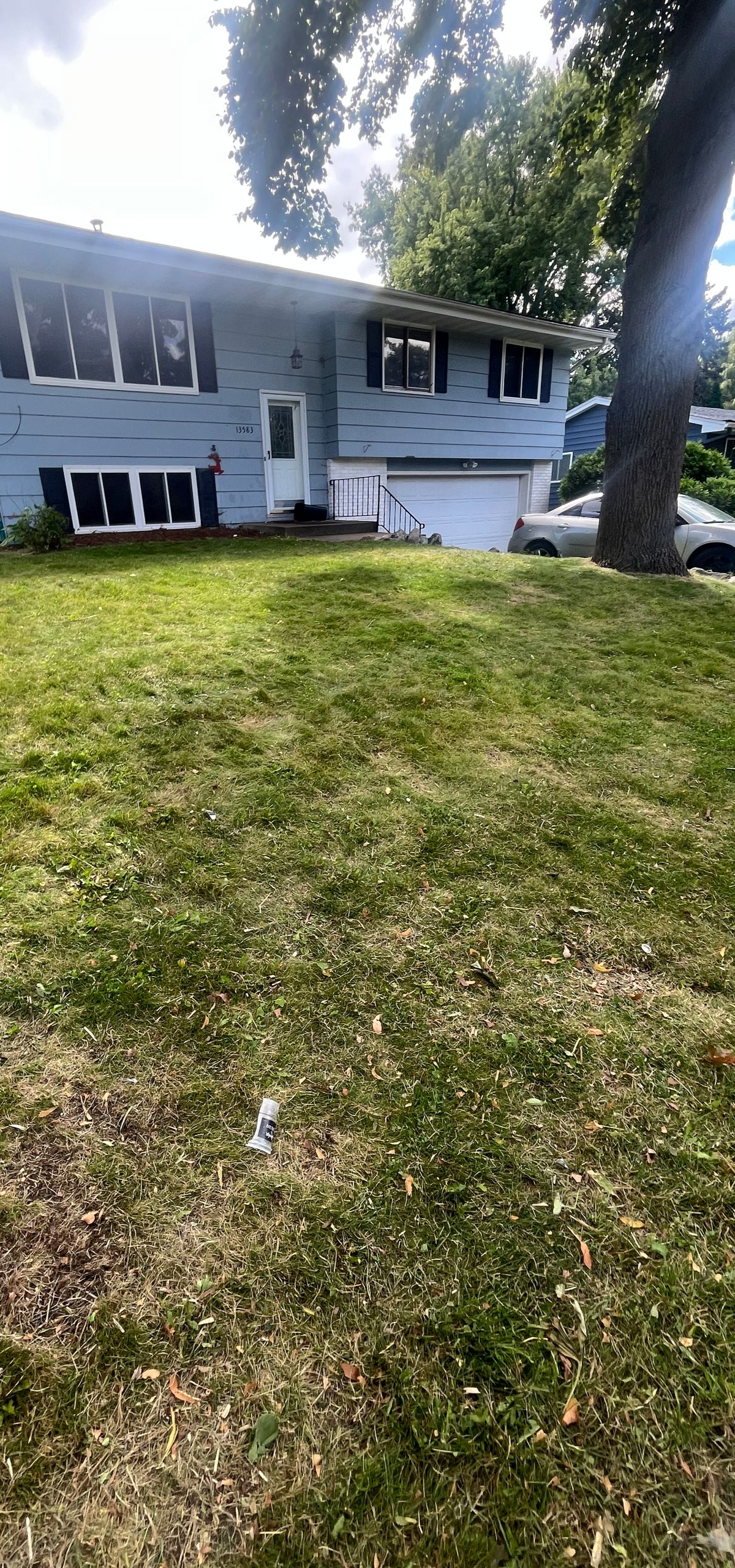Single-story white house with a front lawn and large tree in the yard