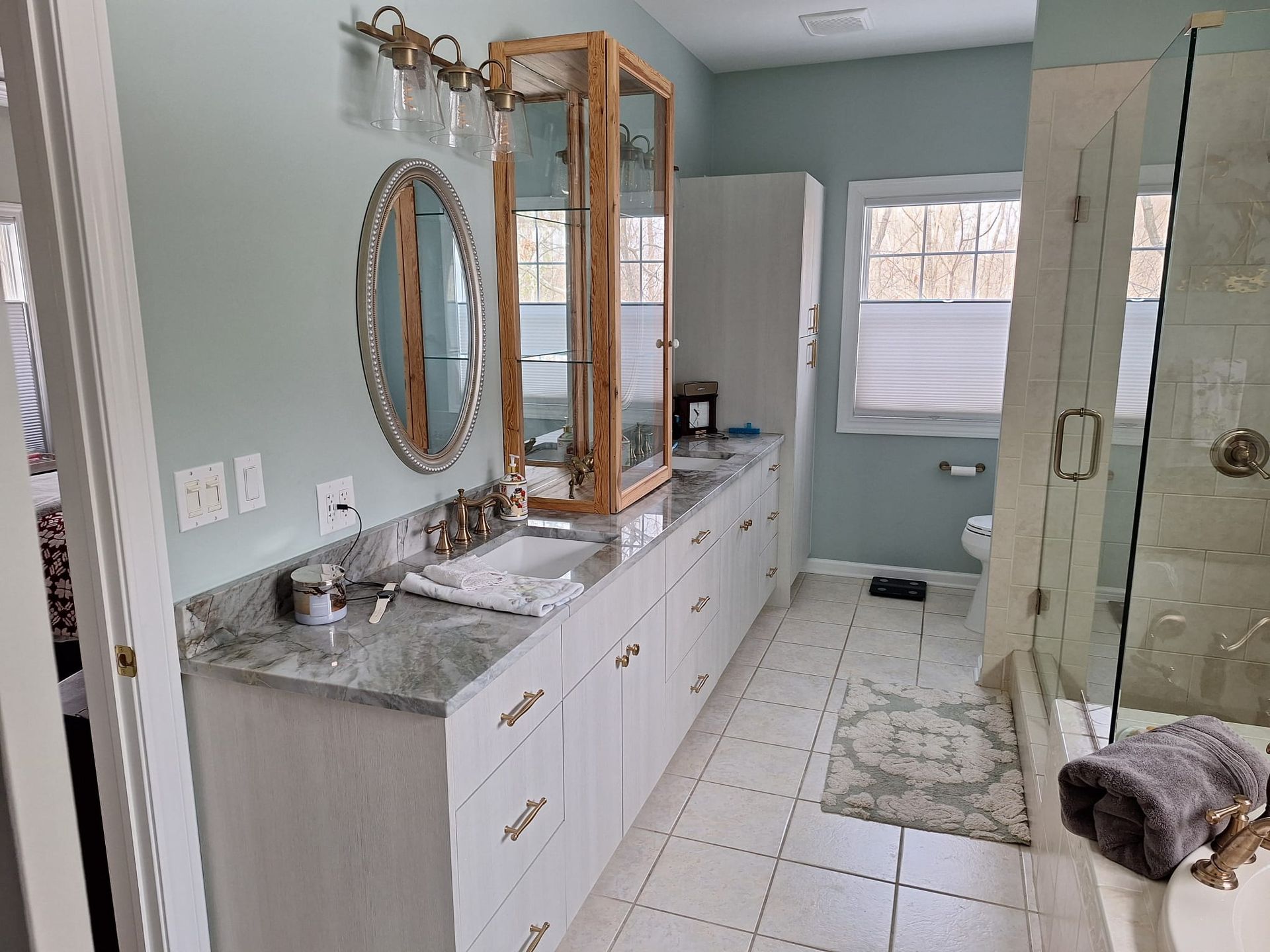 A bathroom with two sinks , a shower , and a window.