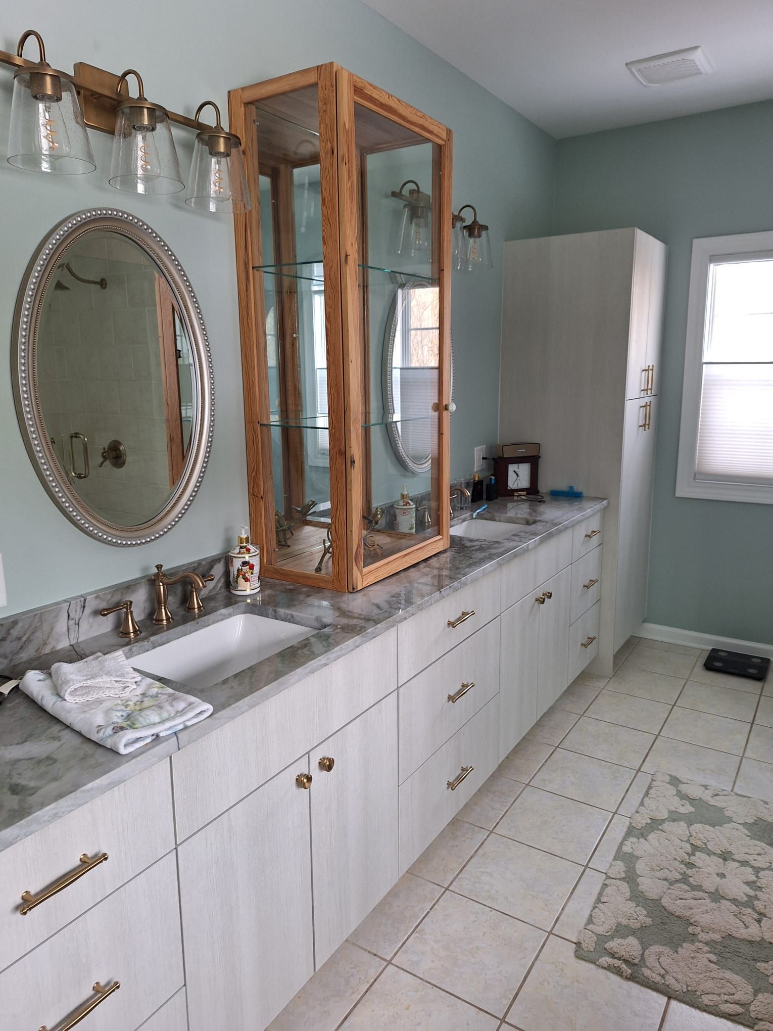 A bathroom with two sinks , a mirror and a cabinet.