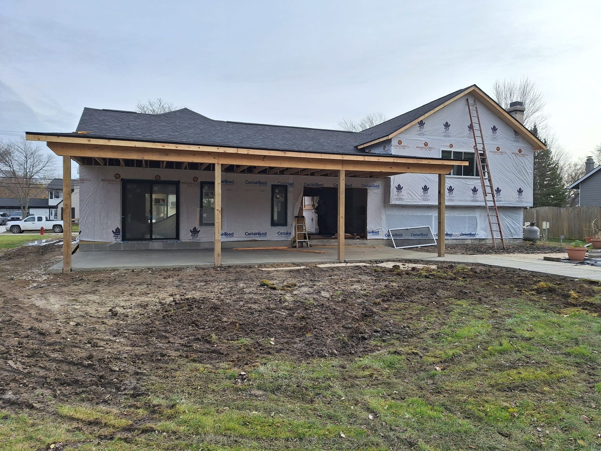 A house under construction with a porch and a lot of dirt in front of it.