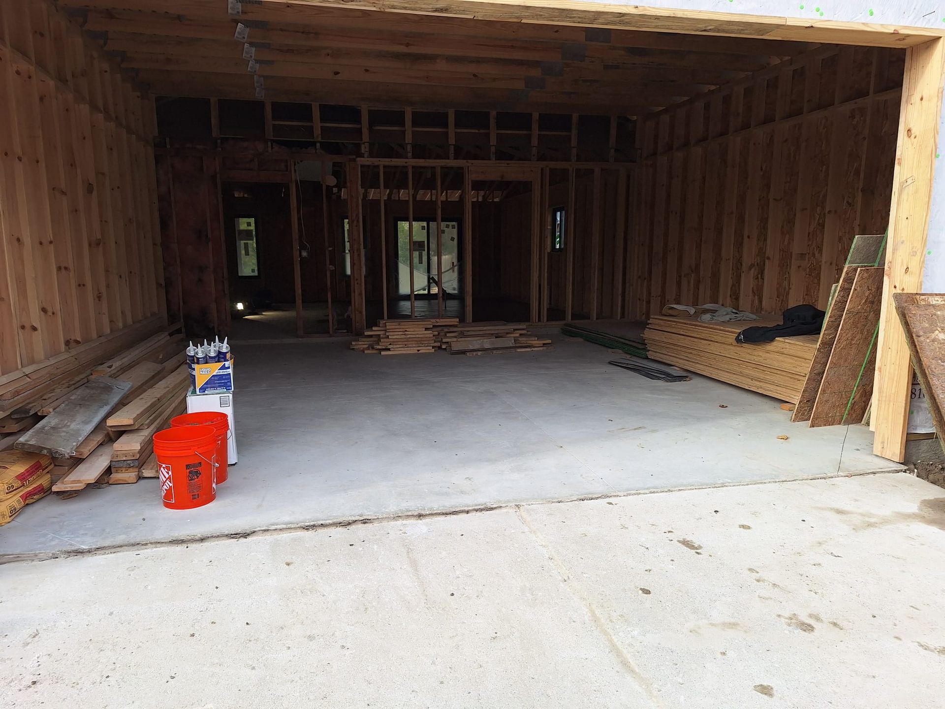 A garage under construction with wooden walls and a concrete floor.