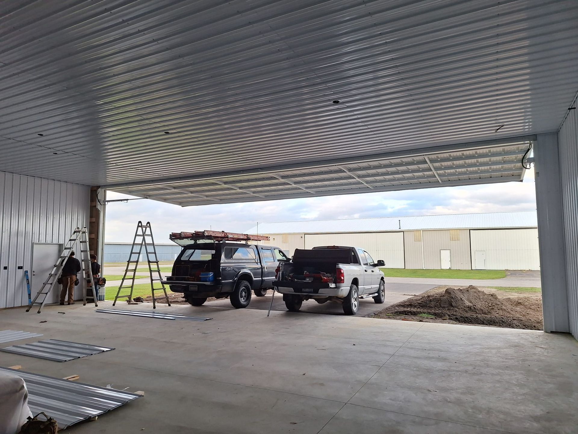 Two trucks are parked in a garage with the door open