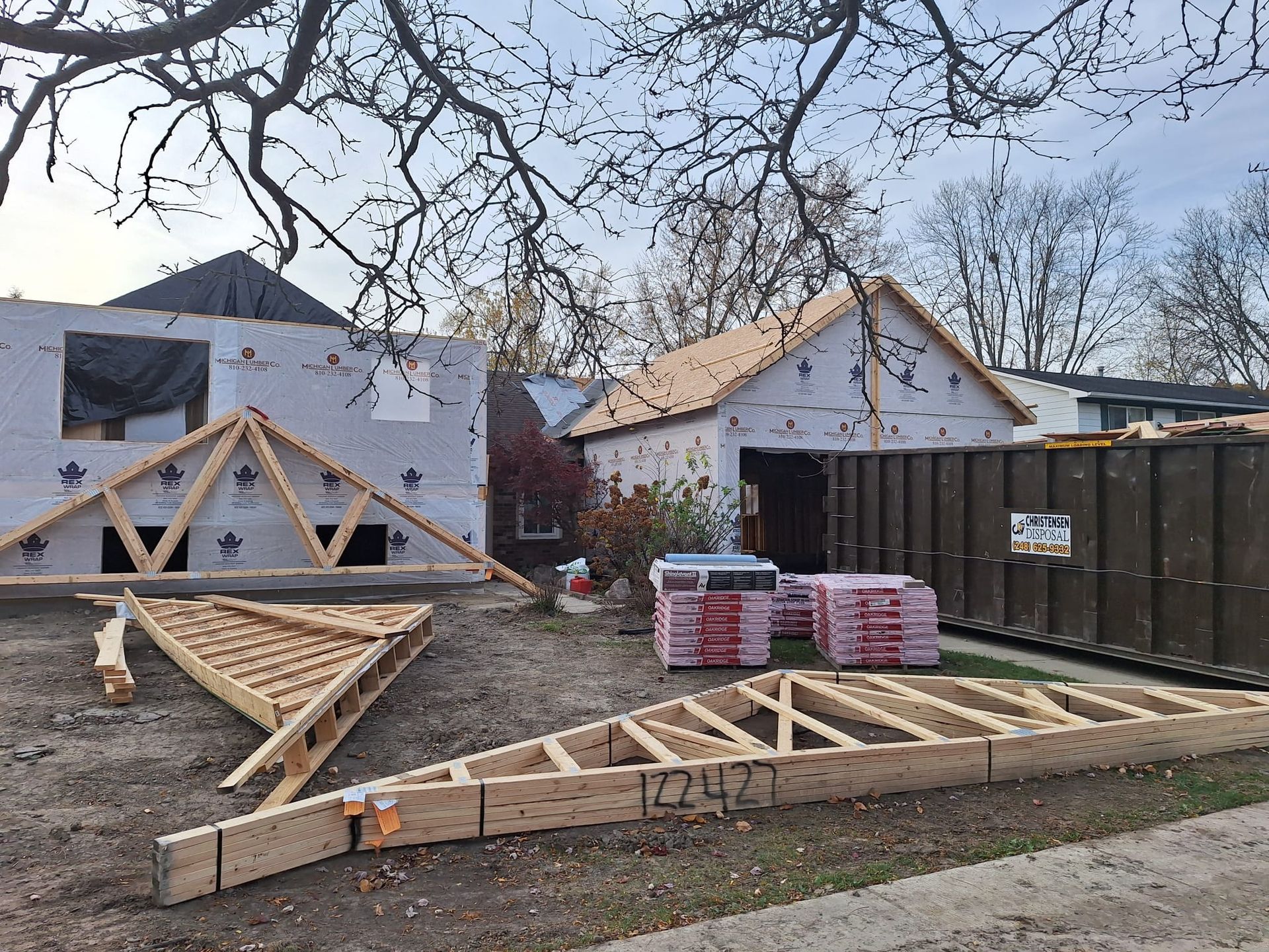 A wooden structure is being built in front of a house under construction.