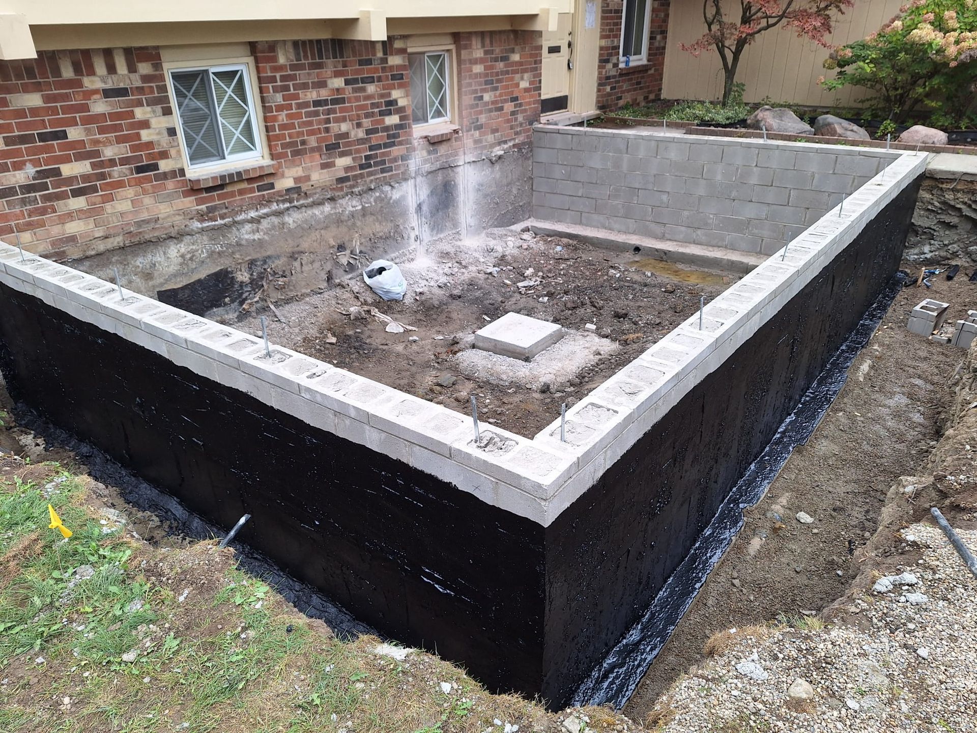 A foundation is being built in front of a brick house.