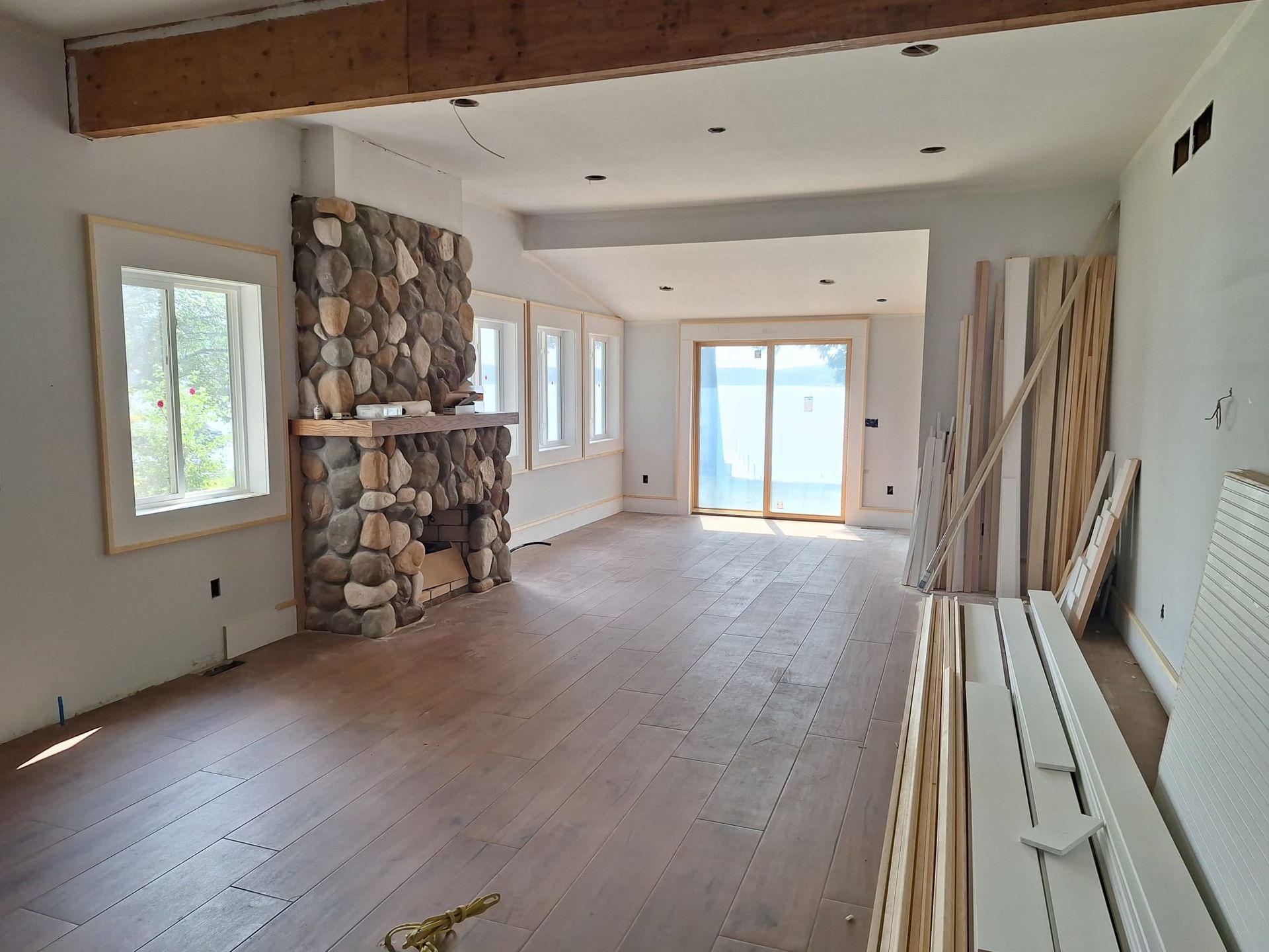 An empty room with a stone fireplace and sliding glass doors