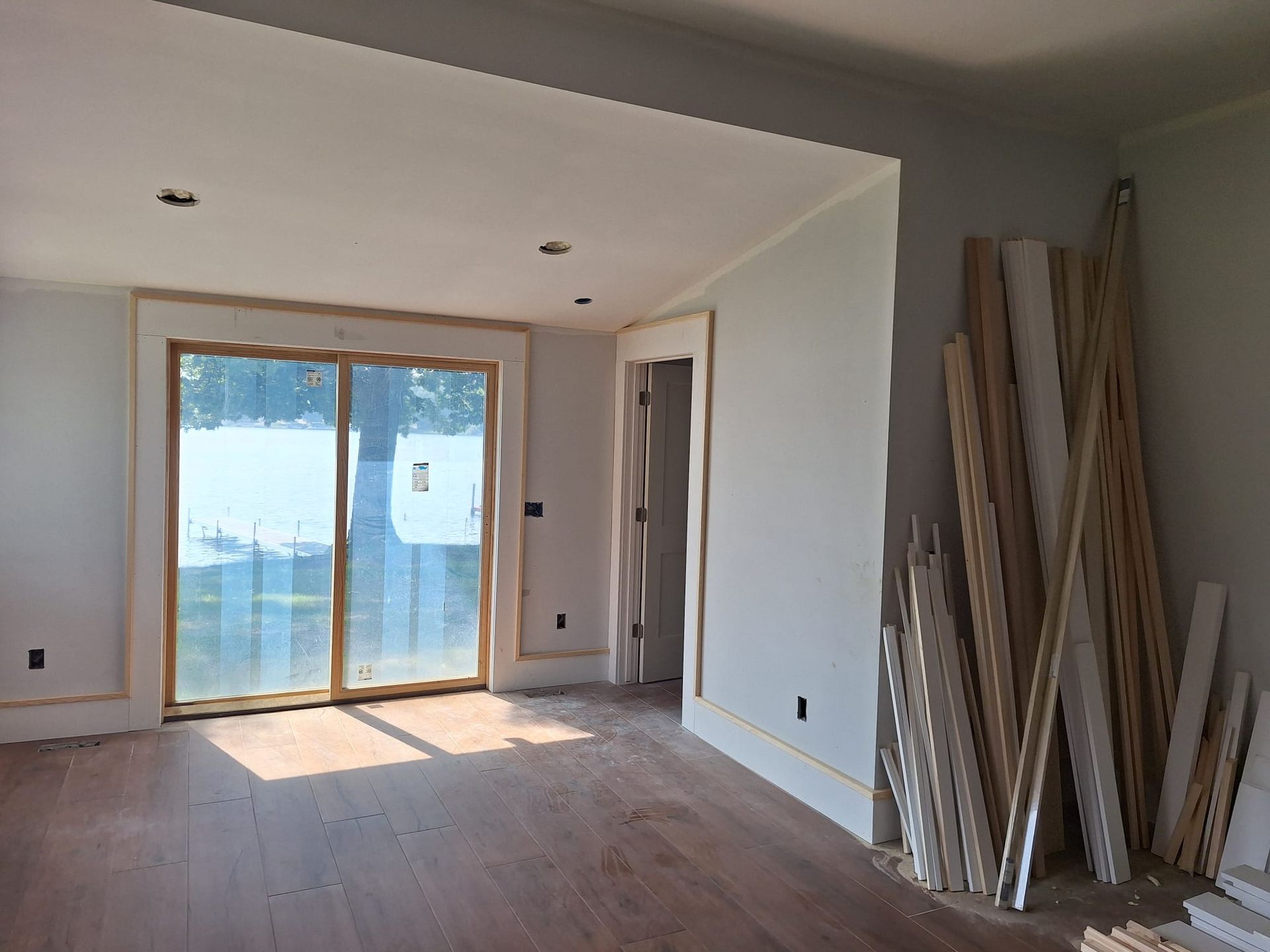 An empty room with a sliding glass door and wooden floors