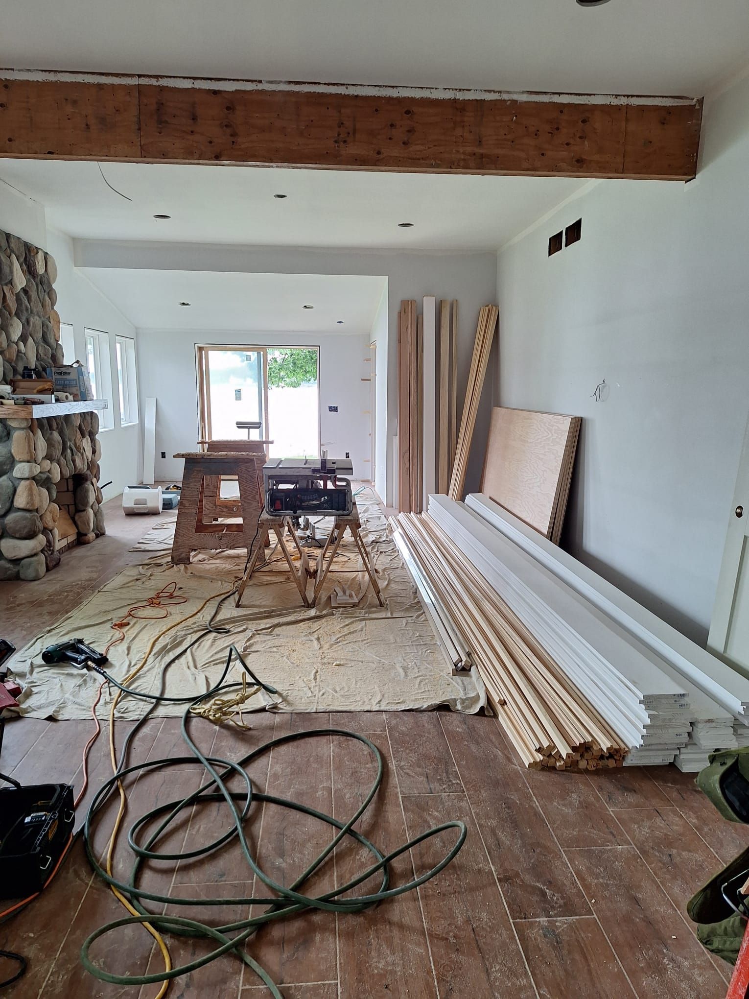 A room with a lot of wood and a lot of wires on the floor.