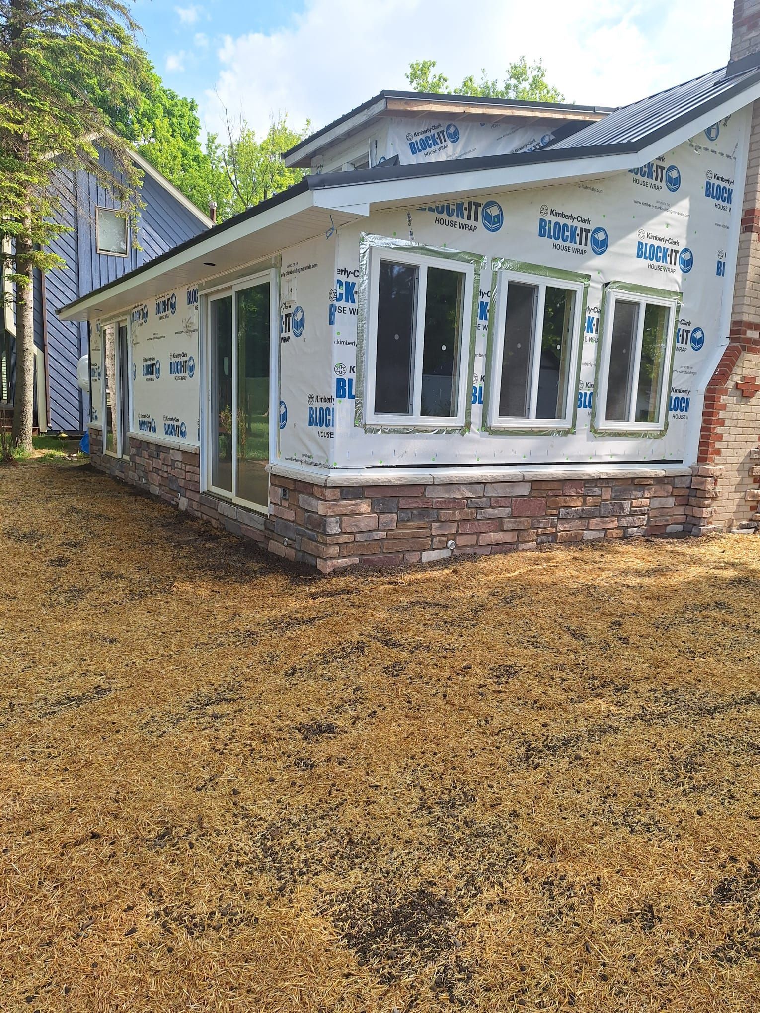 A house with a lot of windows is being built in a backyard.