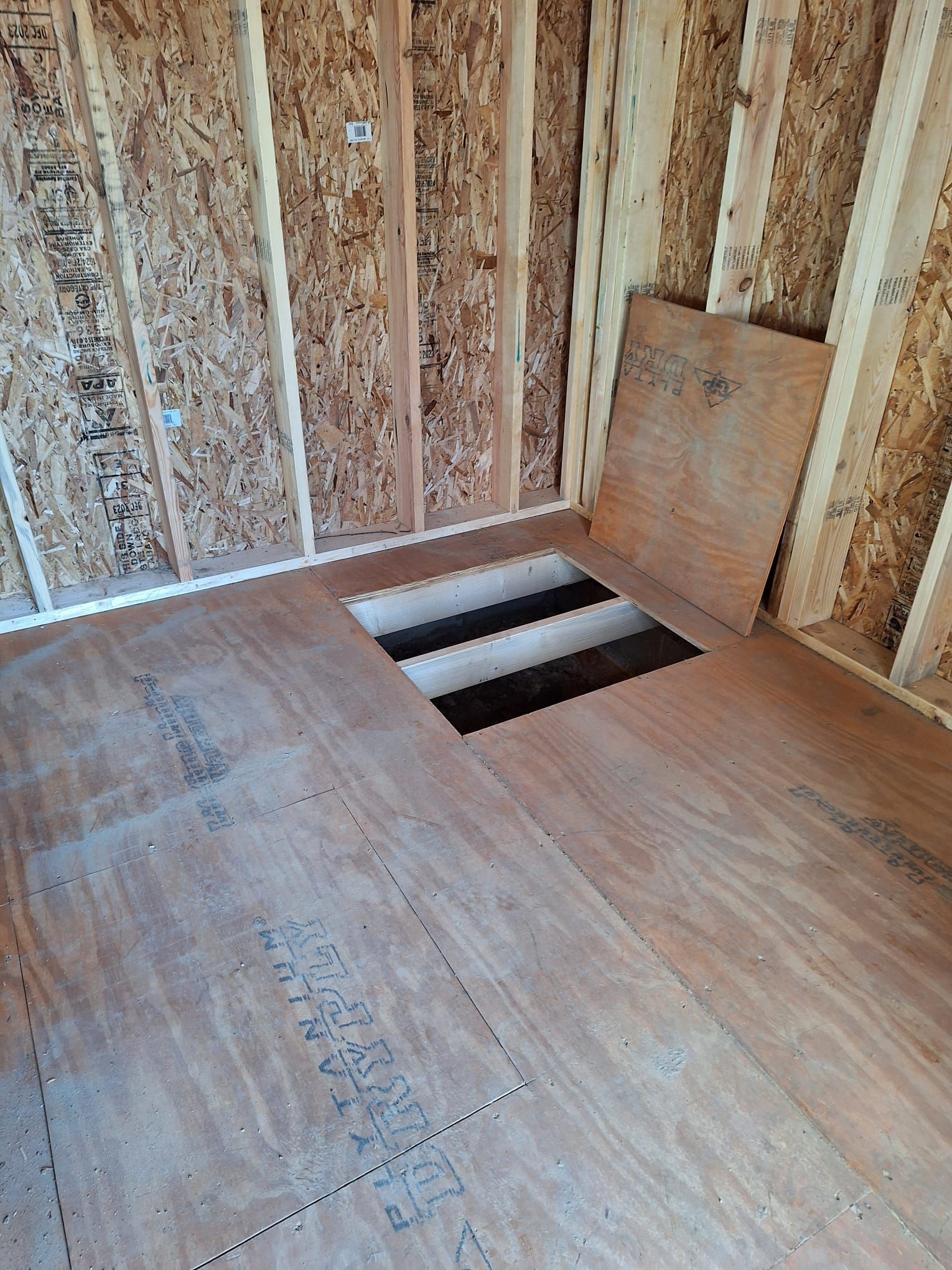 A room with a hole in the floor and a wooden wall.