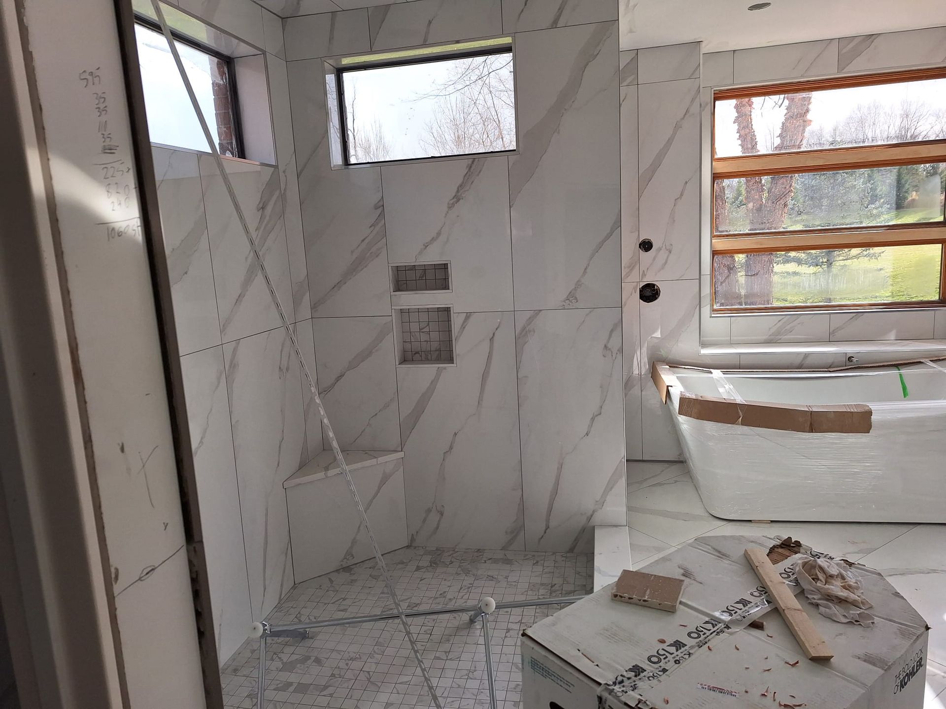 A bathroom under construction with a tub , shower , and window.