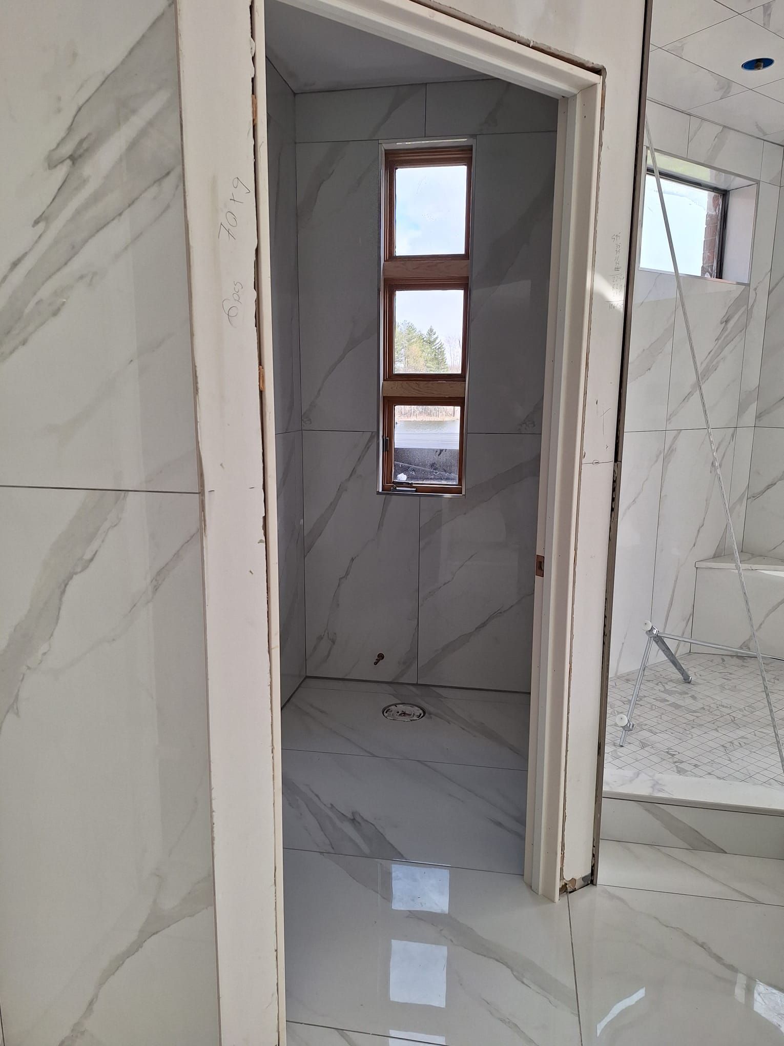 A bathroom under construction with marble tiles and a window.