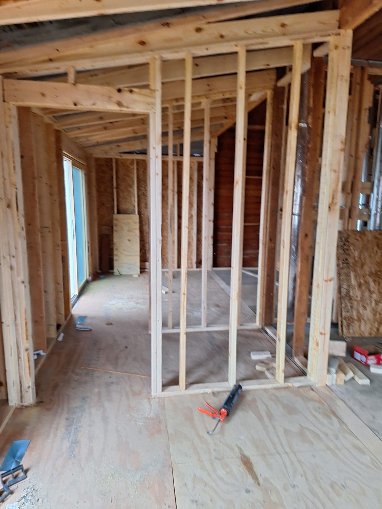 A room under construction with wooden beams and a screwdriver on the floor.