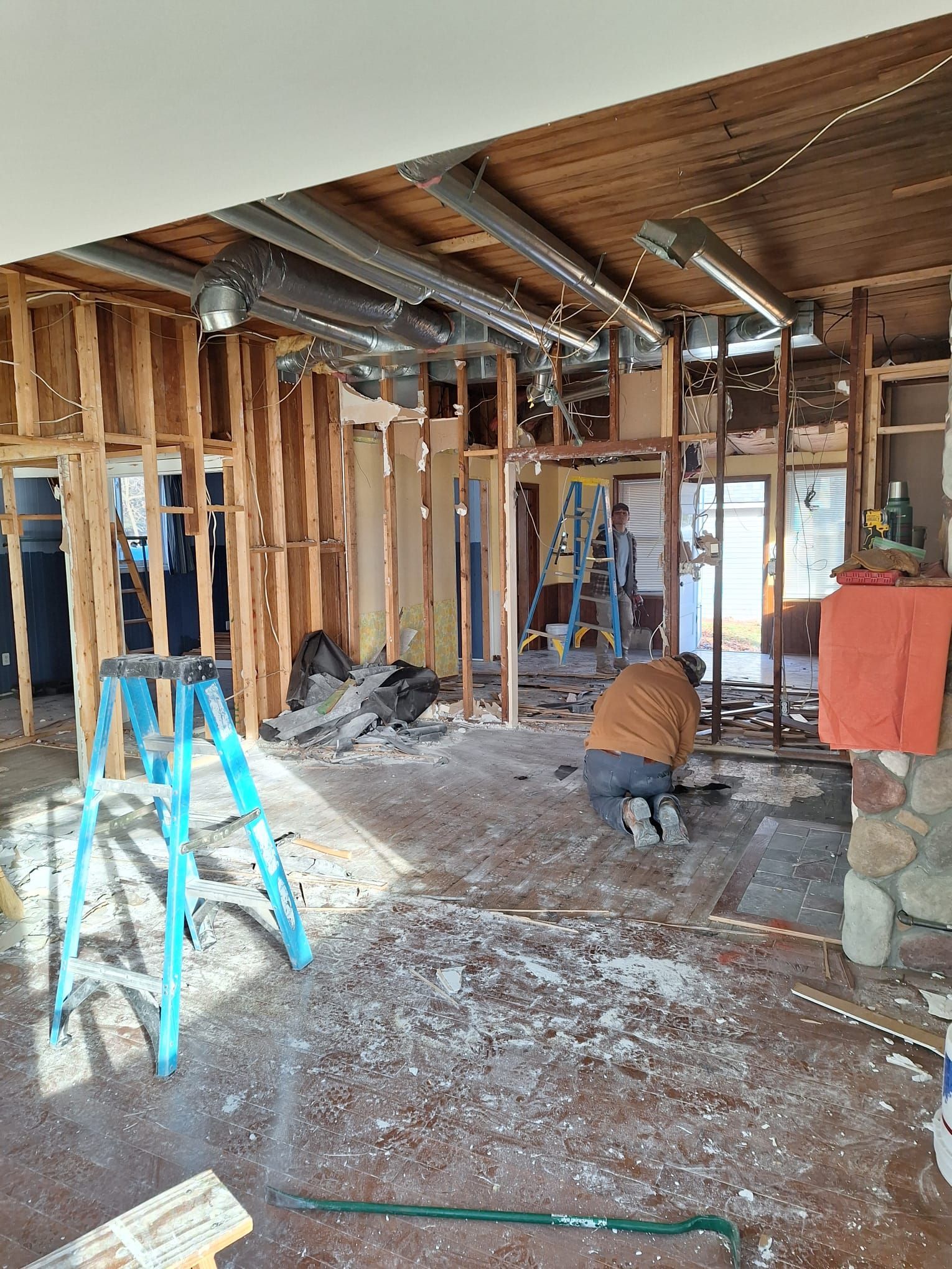 A man is kneeling on the floor in a room under construction.