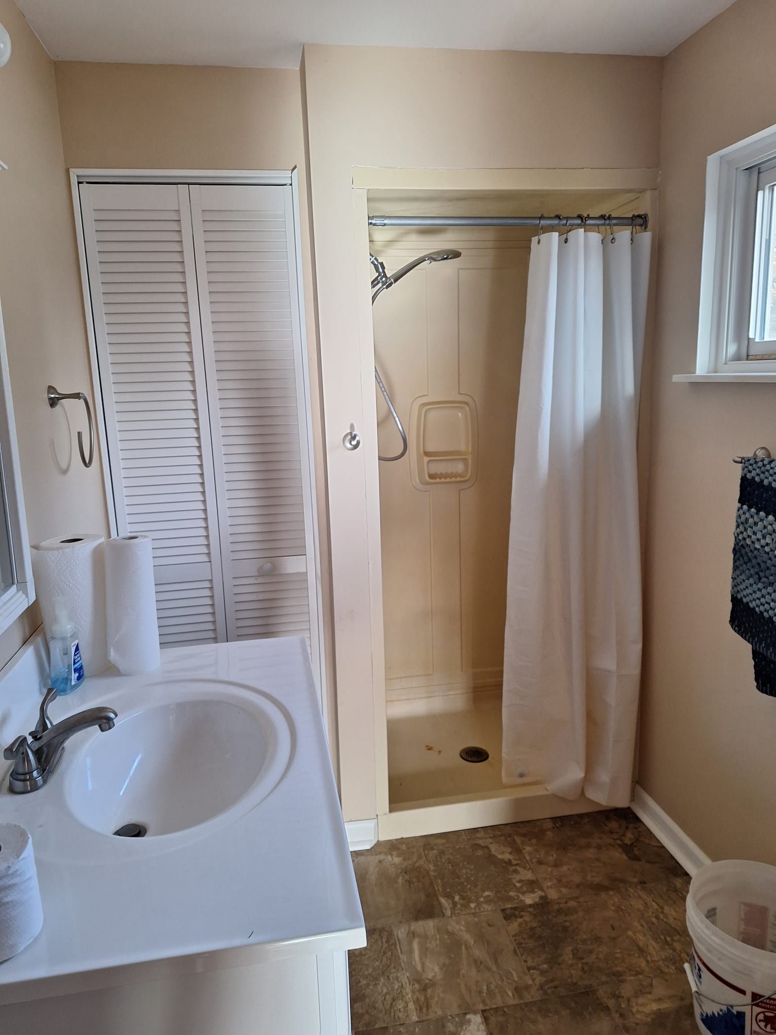 A bathroom with a sink , shower and mirror.