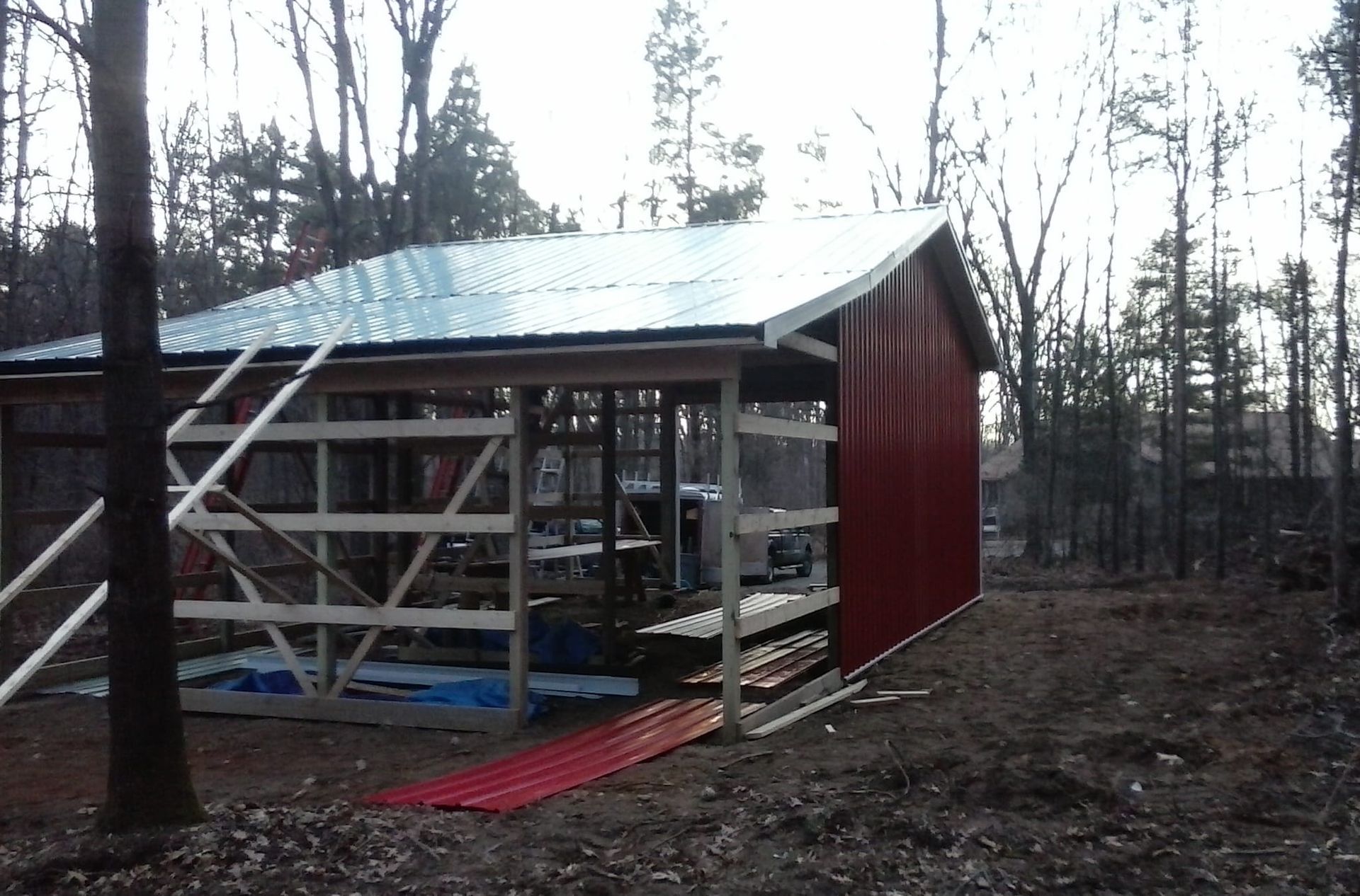 A shed with a metal roof is being built in the woods