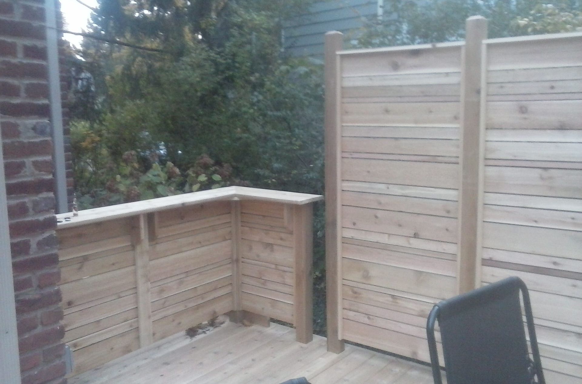 A wooden deck with a fence and a chair