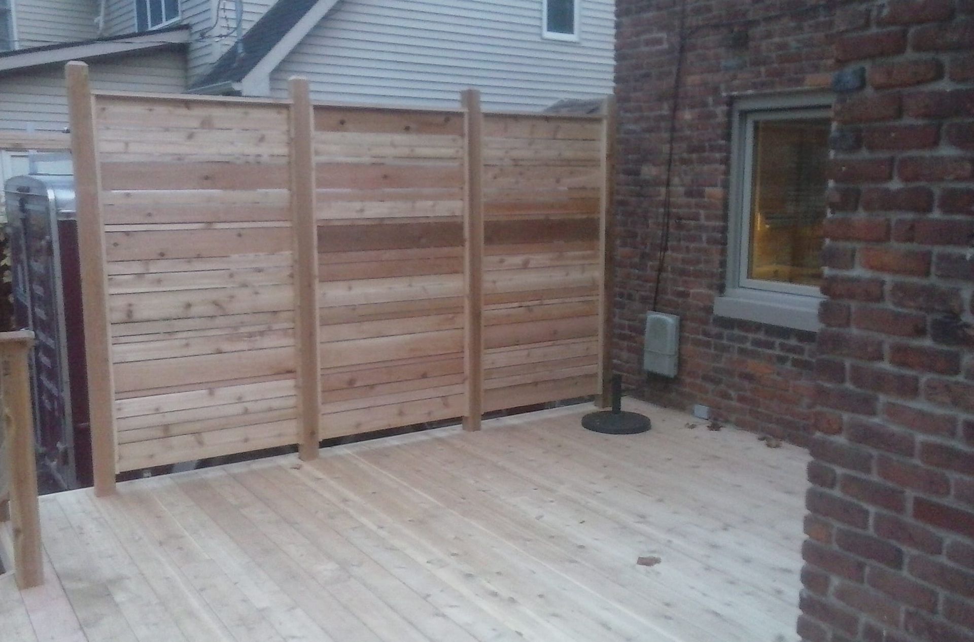 A wooden deck with a wooden fence in front of a brick building