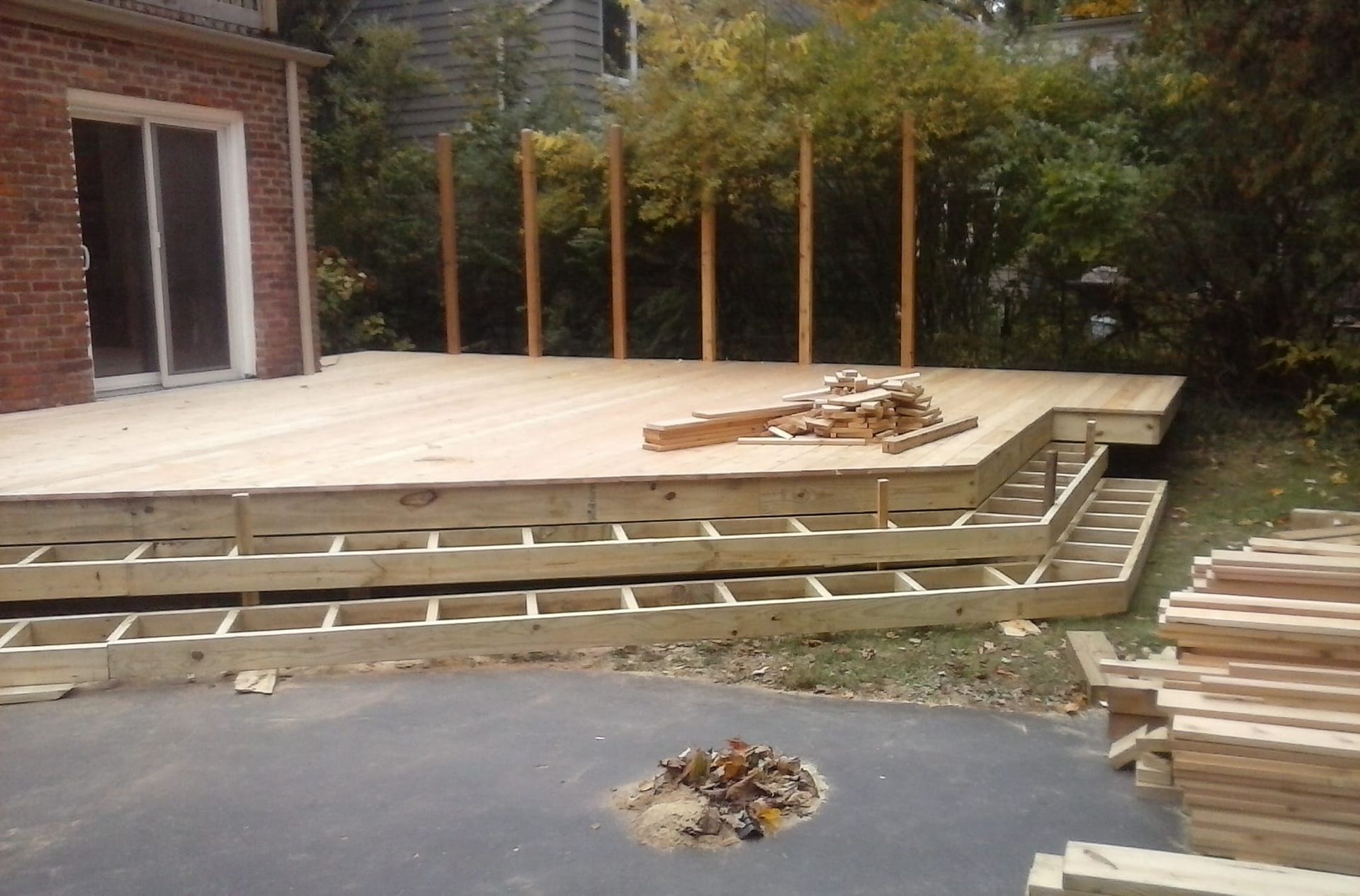 A wooden deck is being built in front of a brick house