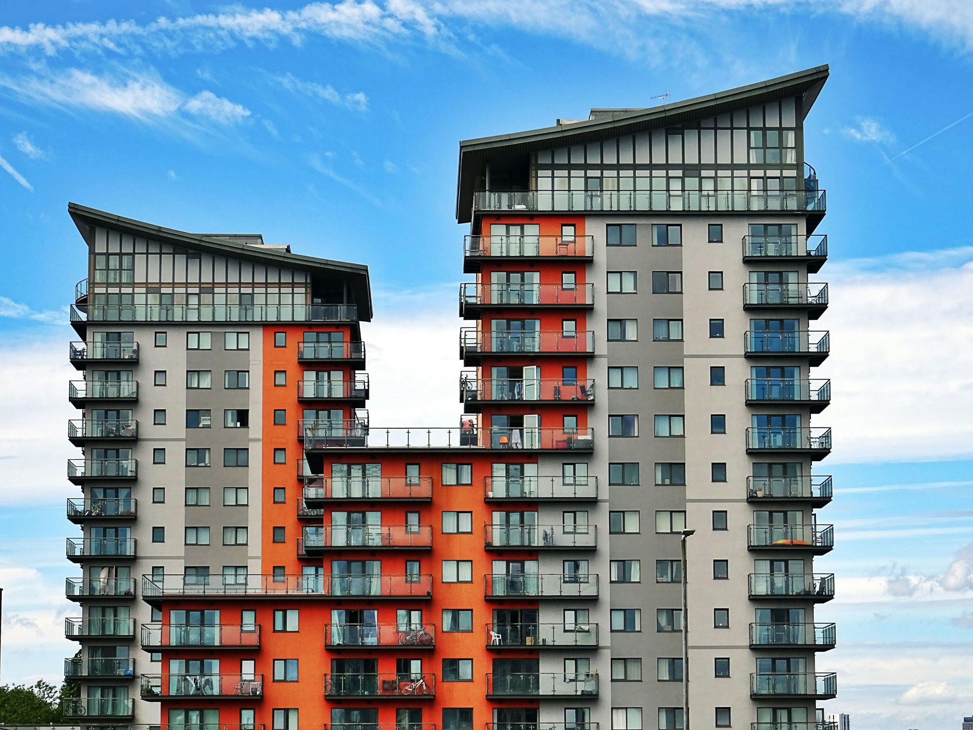 Two tall apartment buildings with balconies against a blue sky