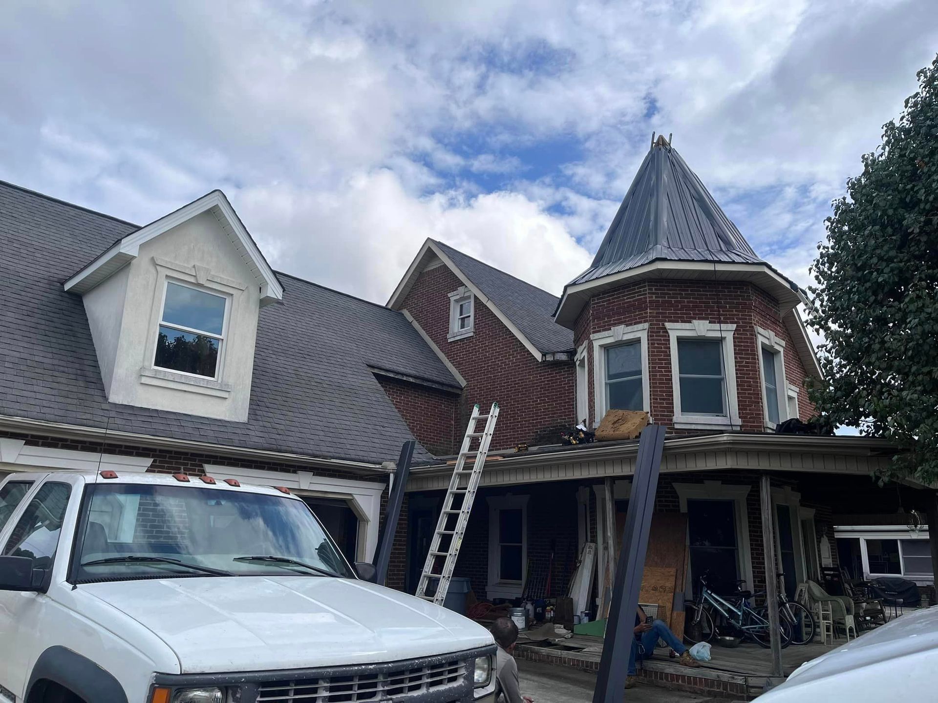 A white truck is parked in front of a large brick house.