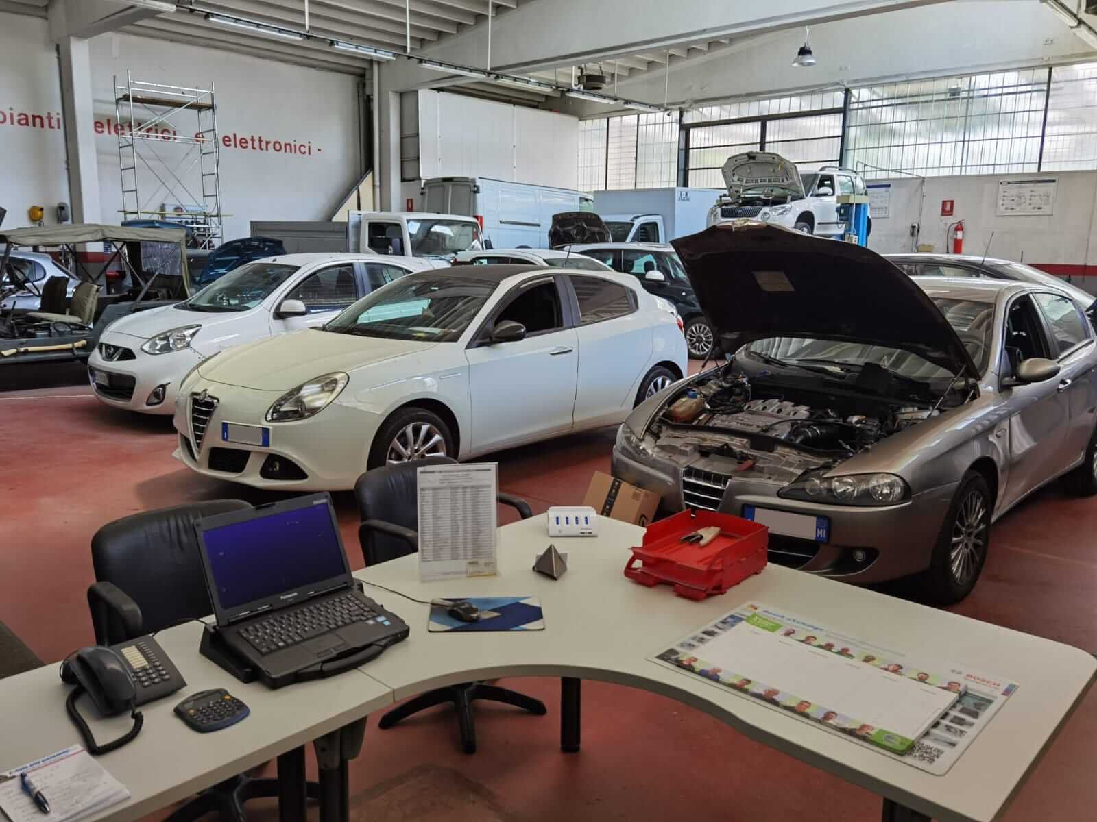 Un meccanico lavora sotto il cofano di un'auto con una chiave inglese in un'officina.