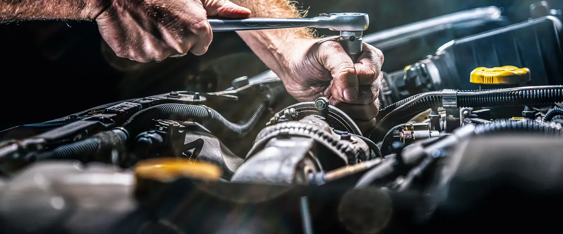 Mechanic working on a car engine with a wrench.