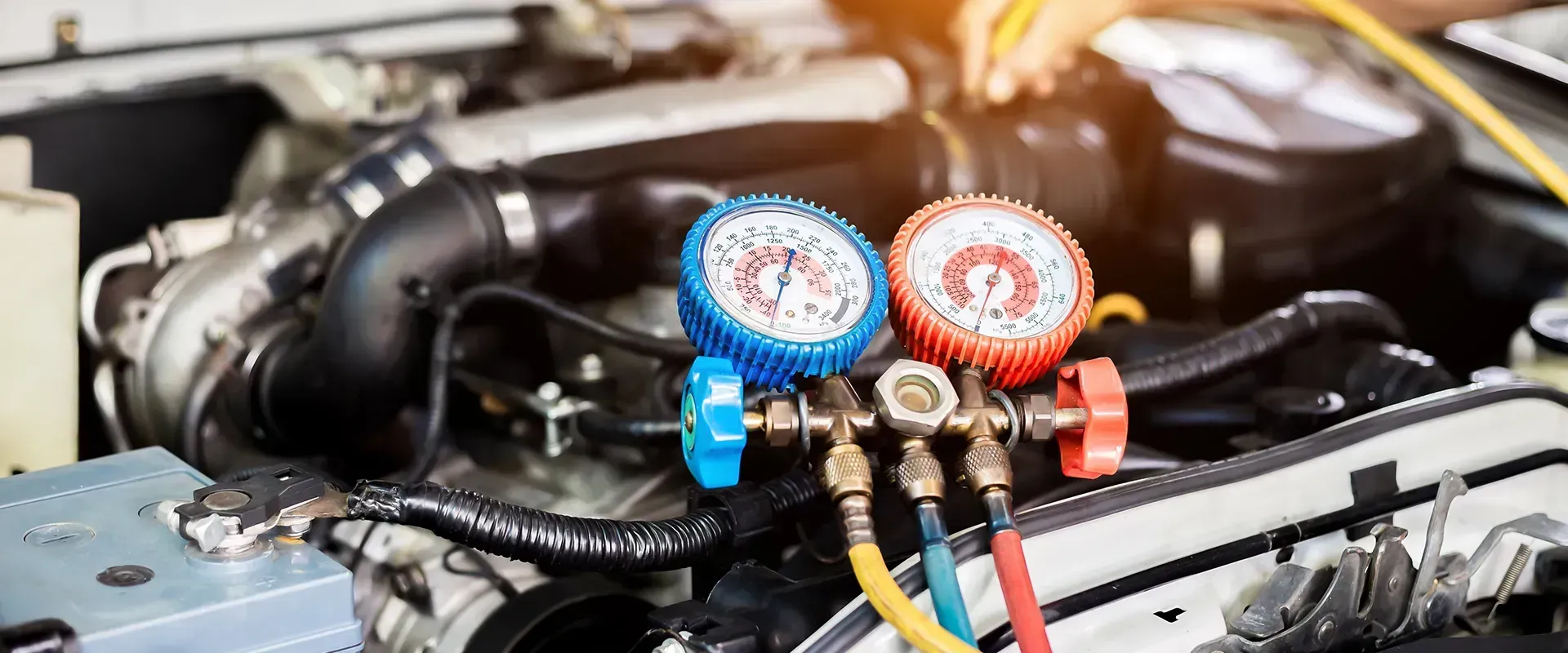 Car engine being serviced with gauges and hoses connected.