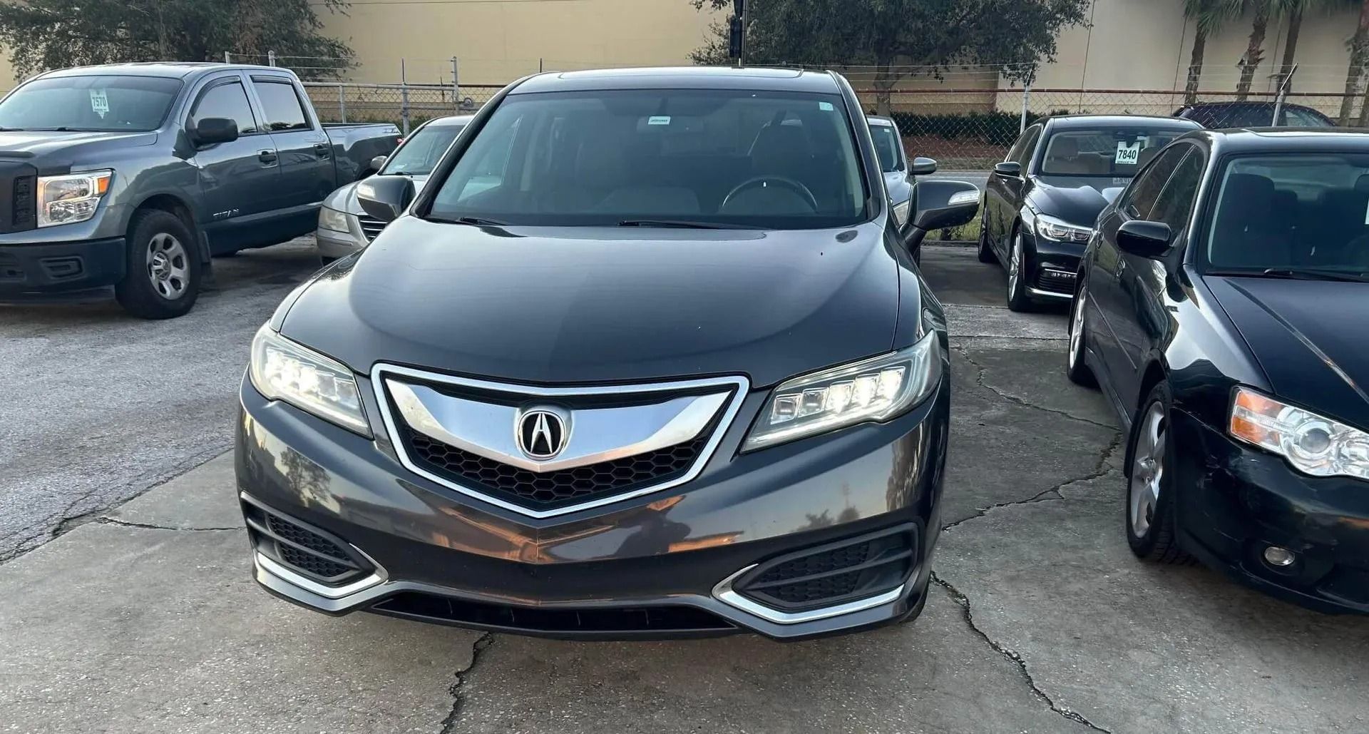 Dark gray Acura RDX SUV parked in a lot, facing forward.