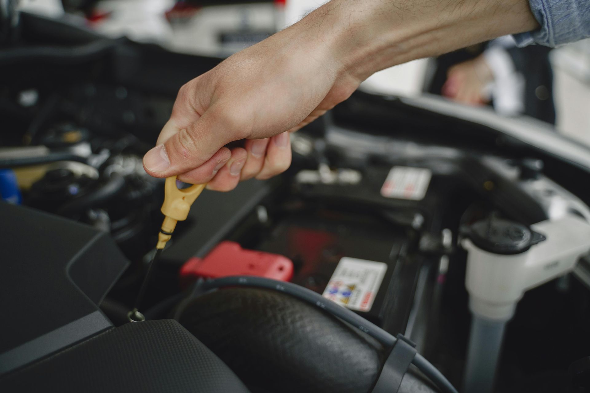 Person checking the oil dipstick of a car engine.