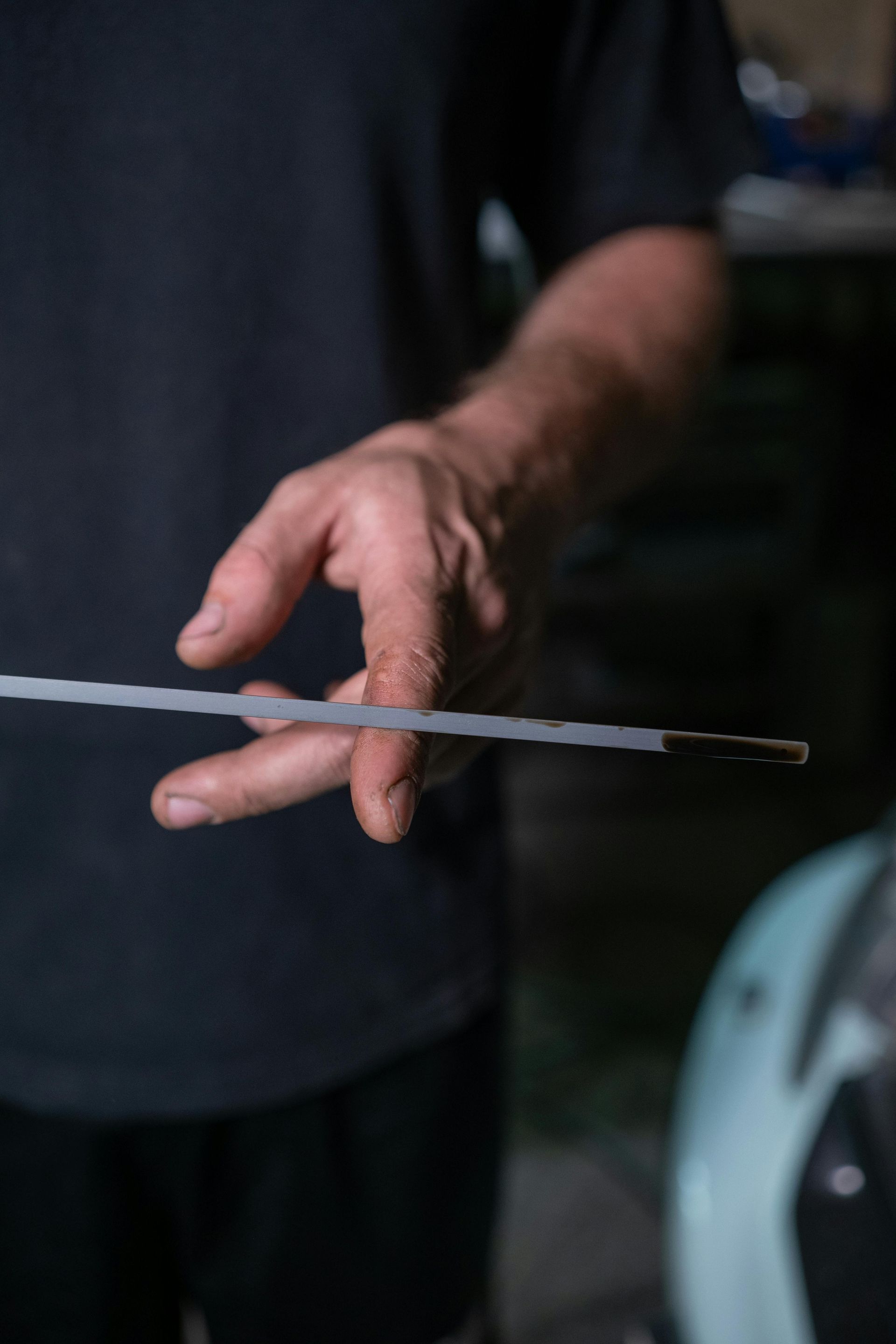 Person holding an oil dipstick, checking the oil level on a car.