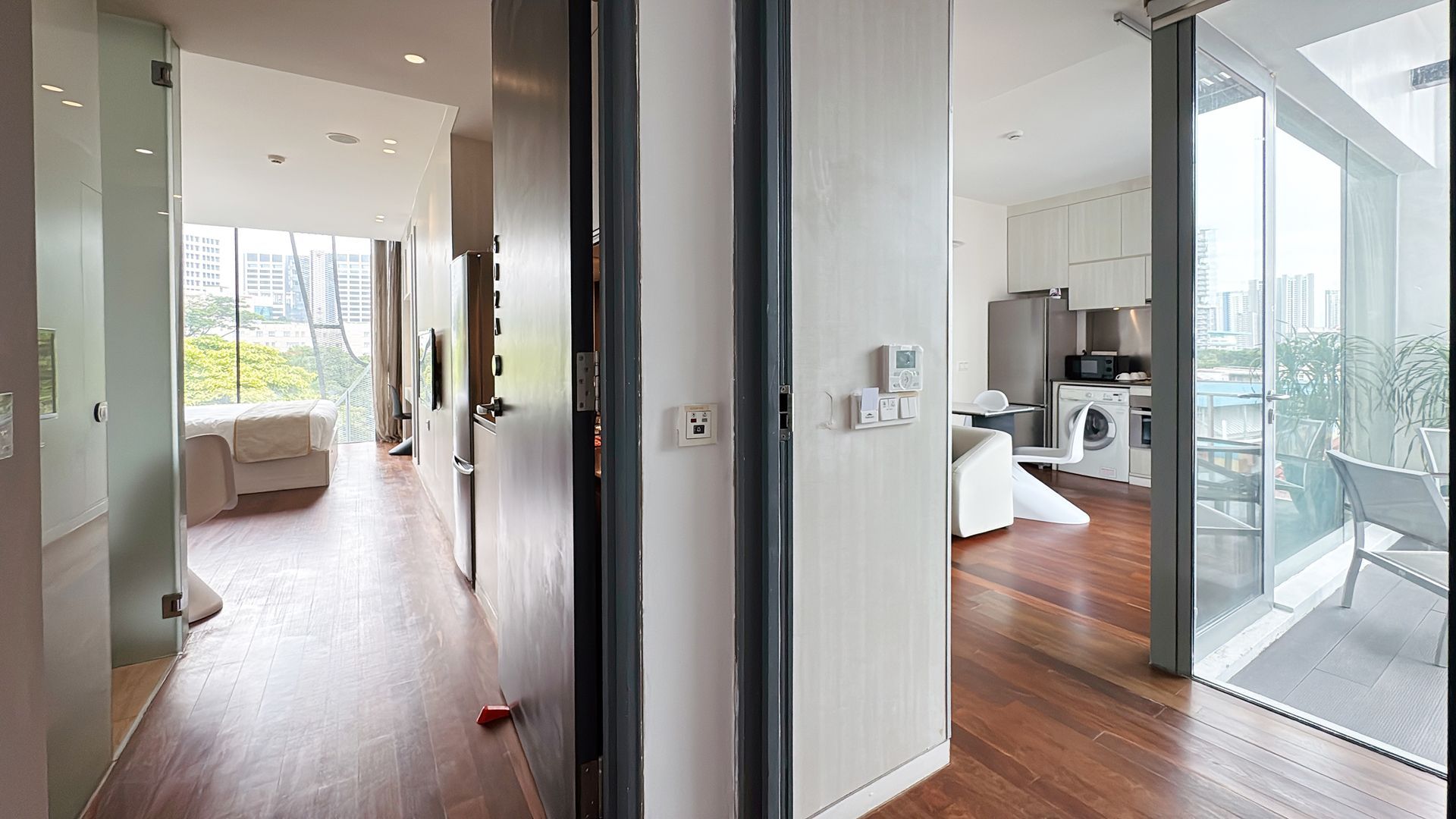Interior view of modern apartment: hallway, kitchen, living room with balcony access; wooden floors.