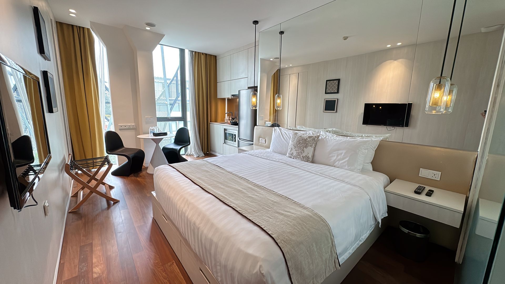 Hotel room with king bed, table with chairs, and large window.