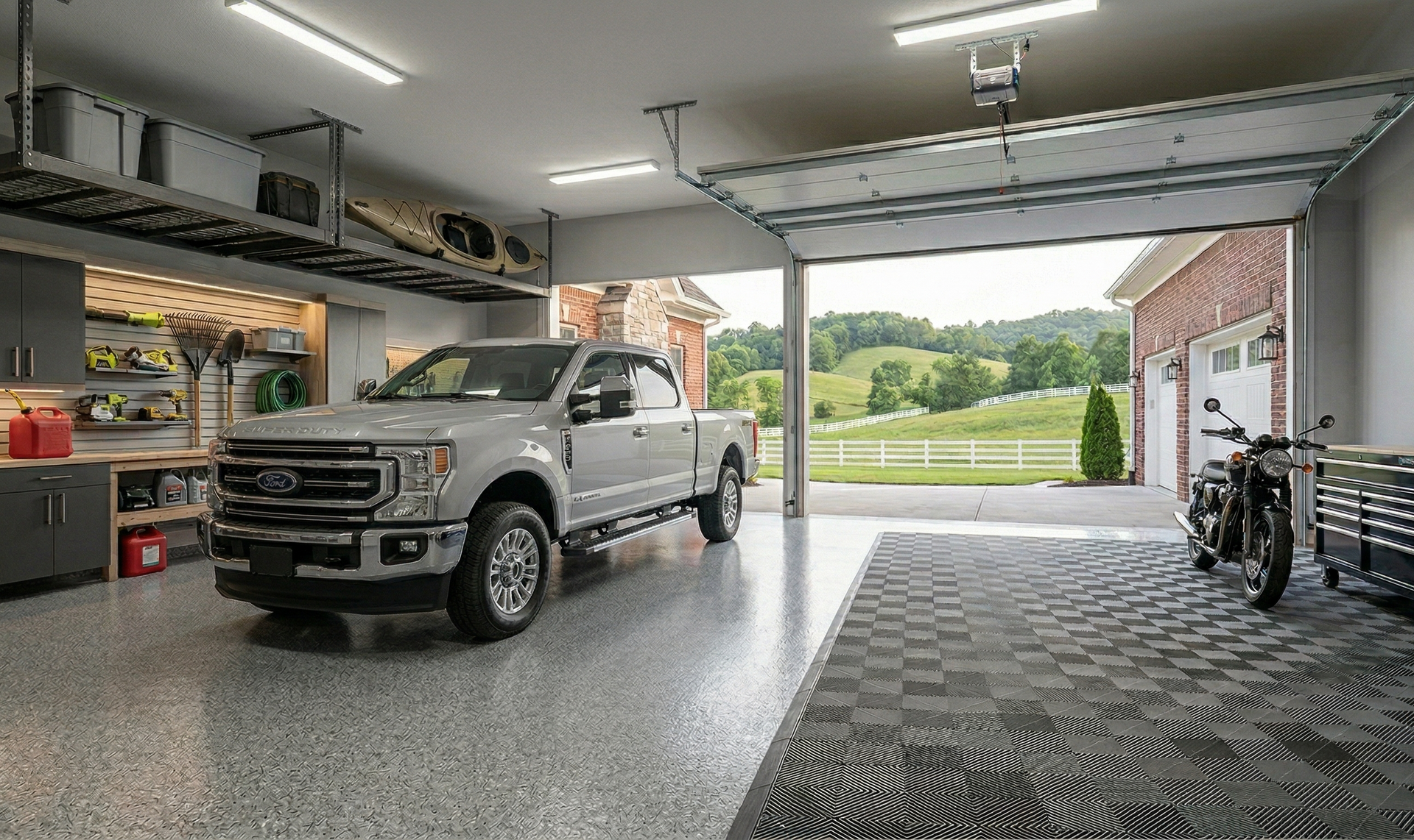 A silver pickup truck and a motorcycle parked in a spacious, organized garage with an open door overlooking a grassy hill.