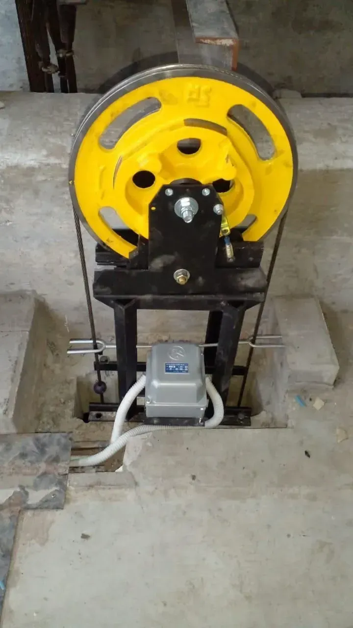 Máquina industrial amarilla montada sobre un bastidor negro con motor y cables en un taller de hormigón.