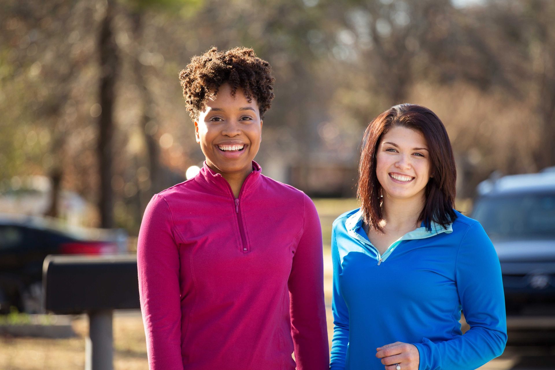 Two women smiling outdoors in athletic wear. Two women smiling outdoors in athletic wear.