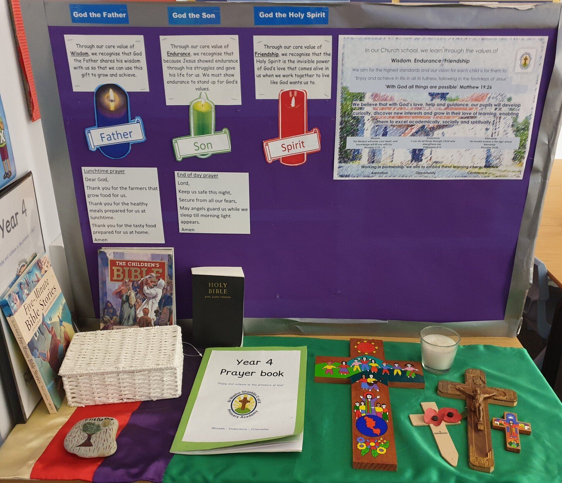 An educational display with religious symbols, texts, and a Year 4 prayer book. Purple backdrop.