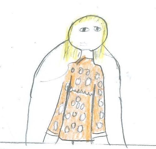 Blond-haired person wearing a brown patterned shirt, with a white backdrop.