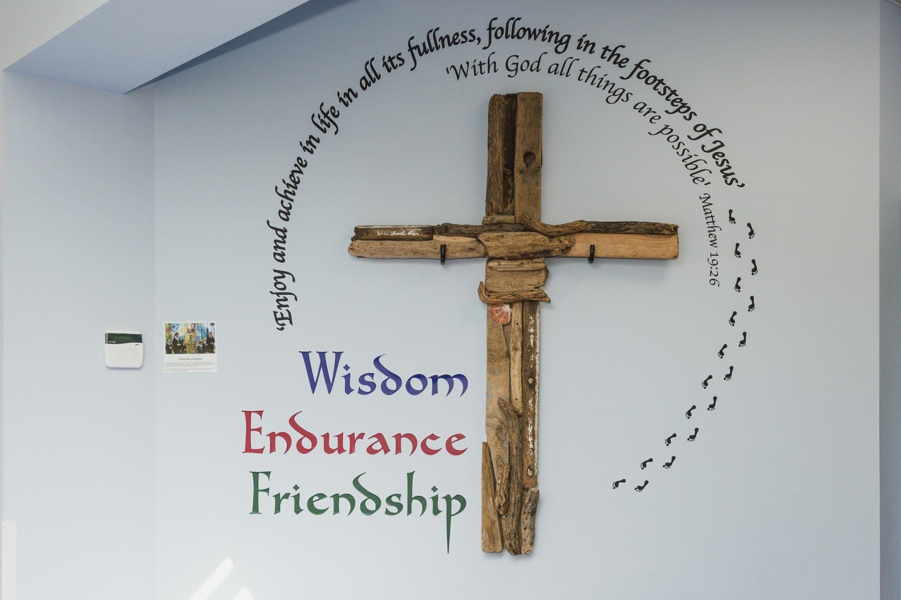 Wooden cross on wall with text: