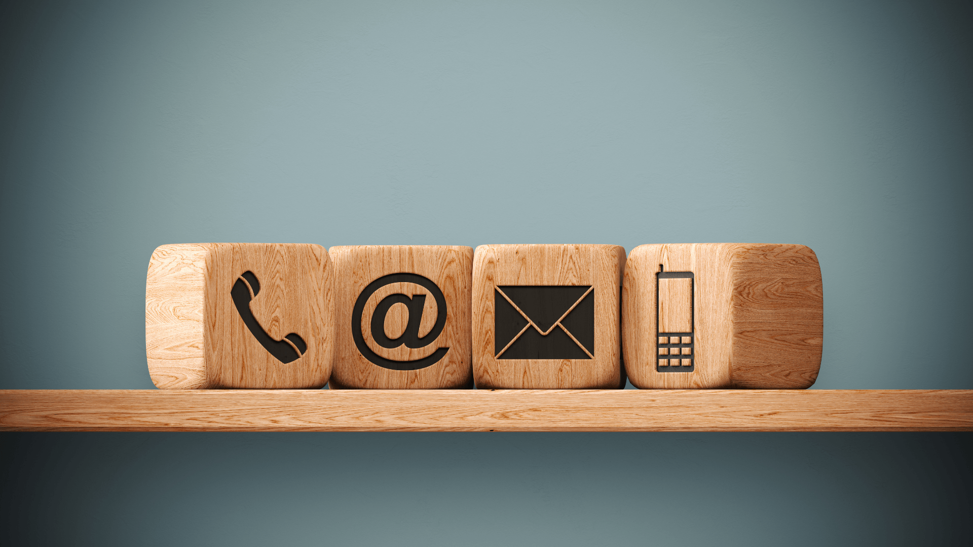 Wooden blocks with phone, email, letter, and mobile phone icons.