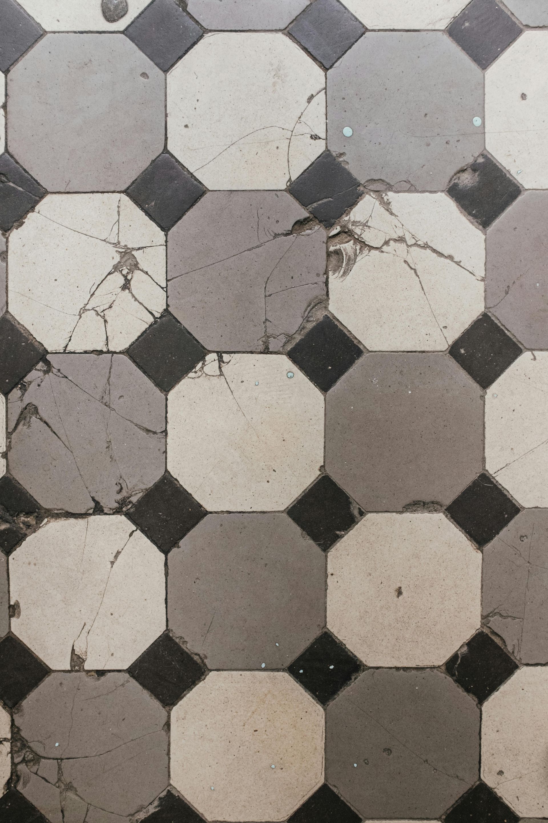 Worn geometric tile floor with gray, white, and black octagonal patterns and cracks
