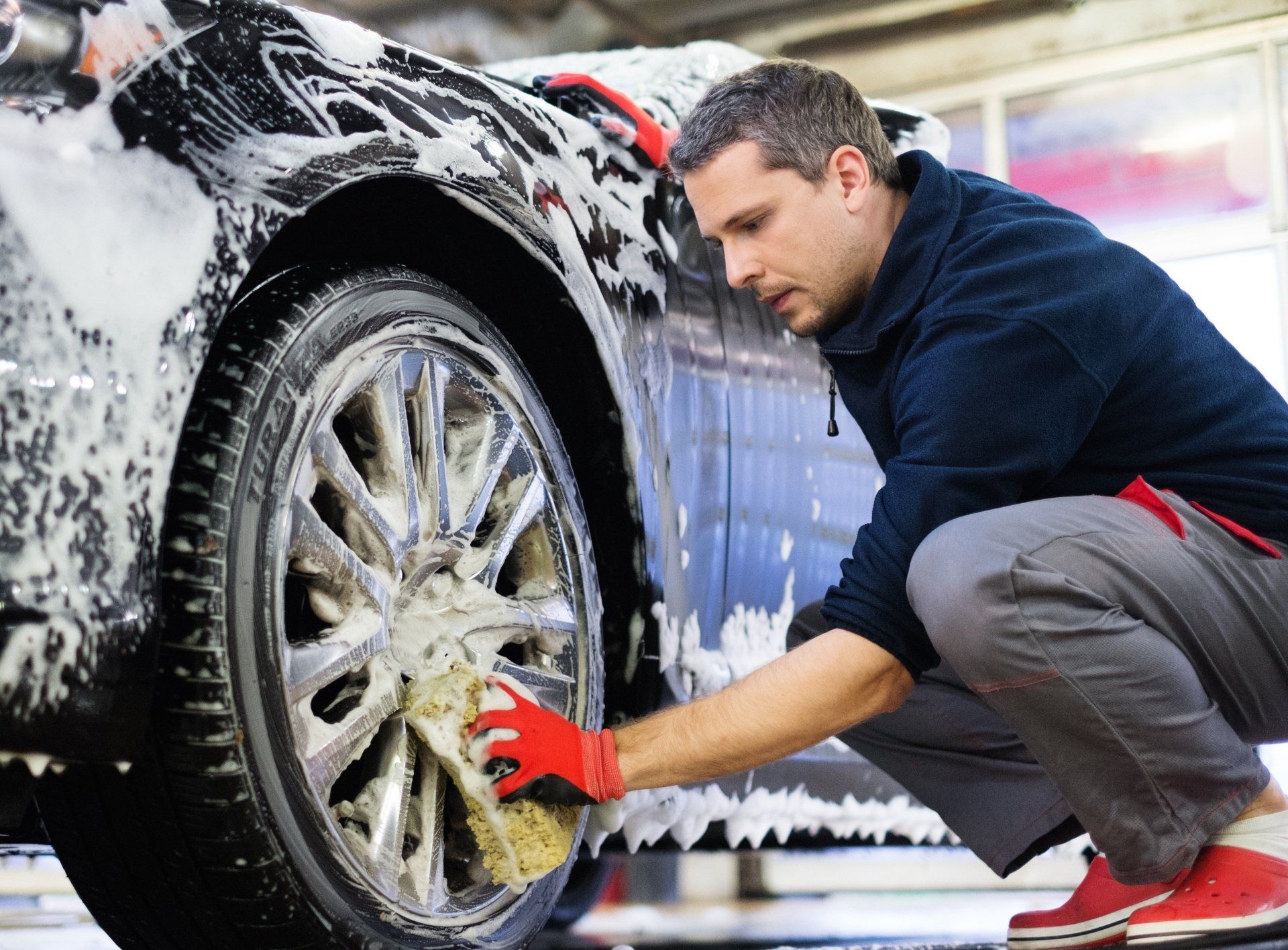 clicking this image will do nothing A man washing a wheel with a sponge