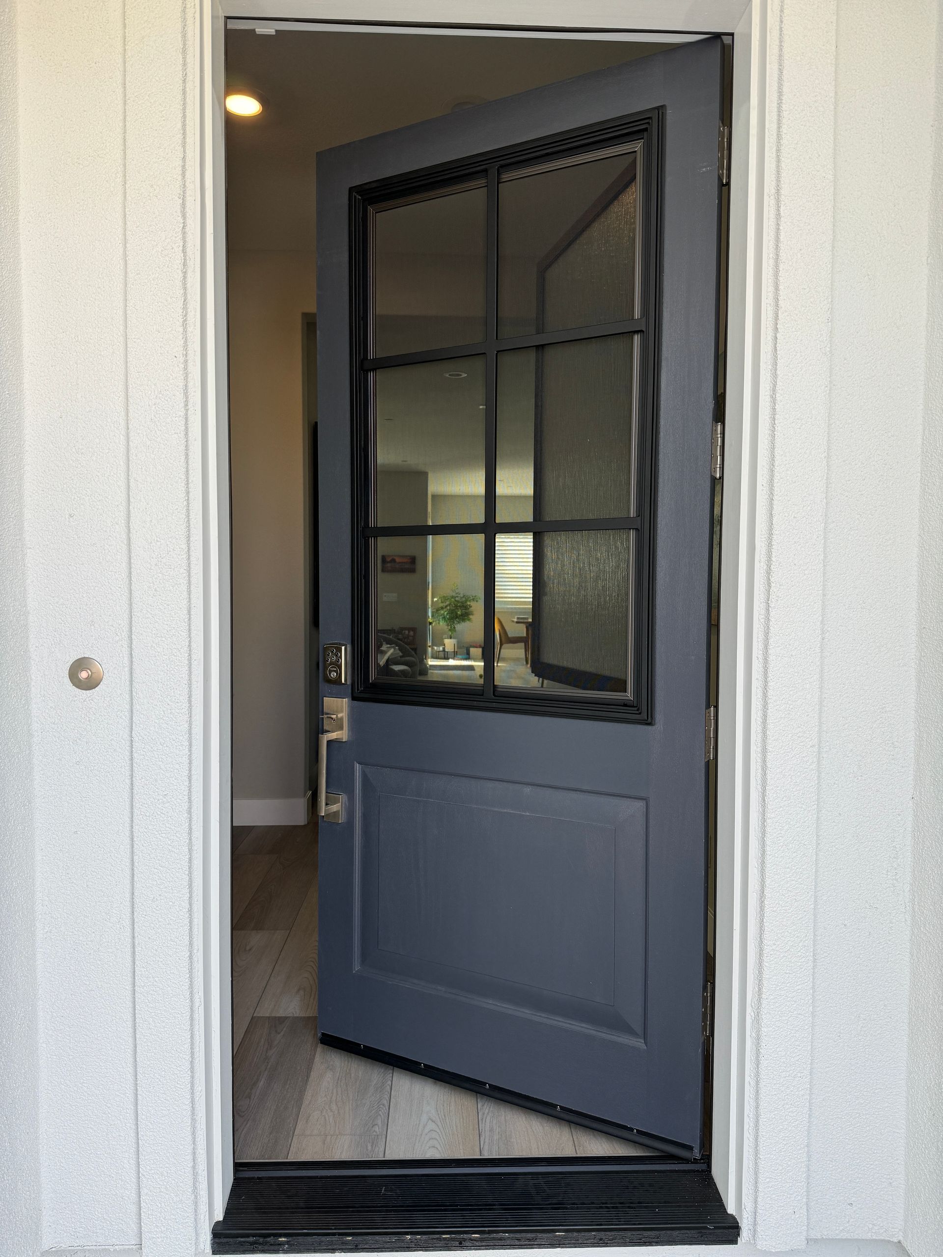 A blue door with a black frame is open to a living room.
