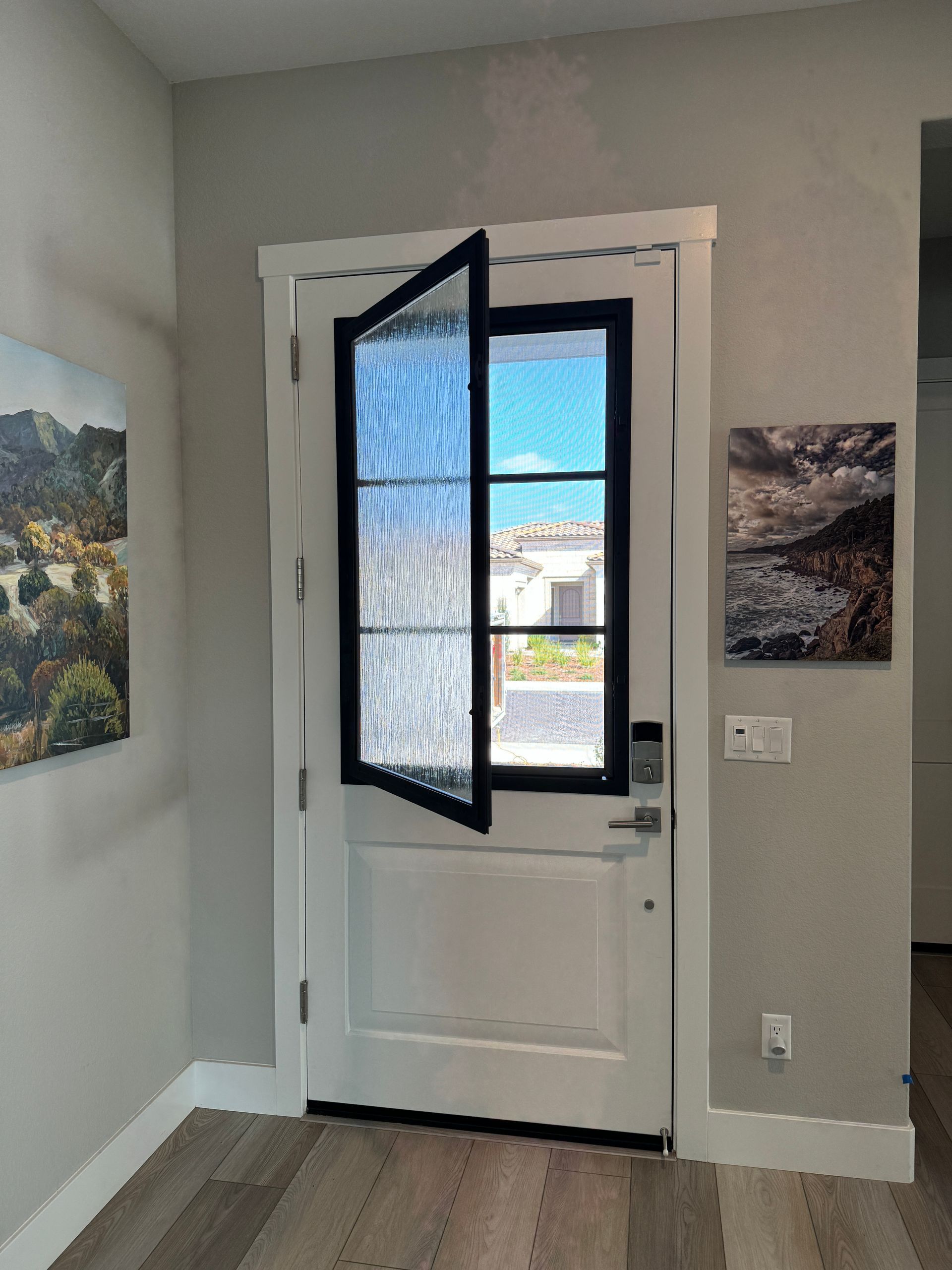 A white door with a black frame is open in a hallway.