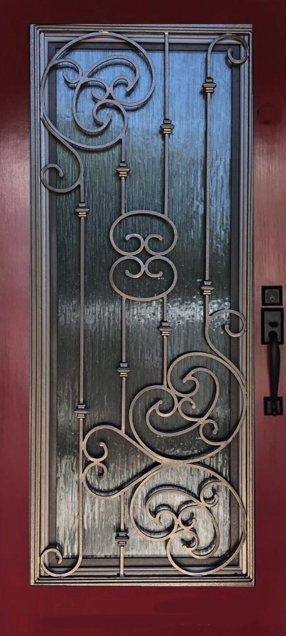 A wrought iron door is on a red wall.