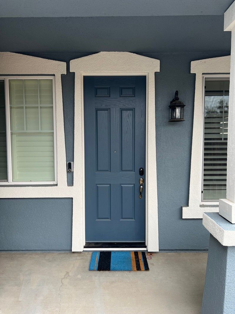 A blue door with white trim is on a blue house