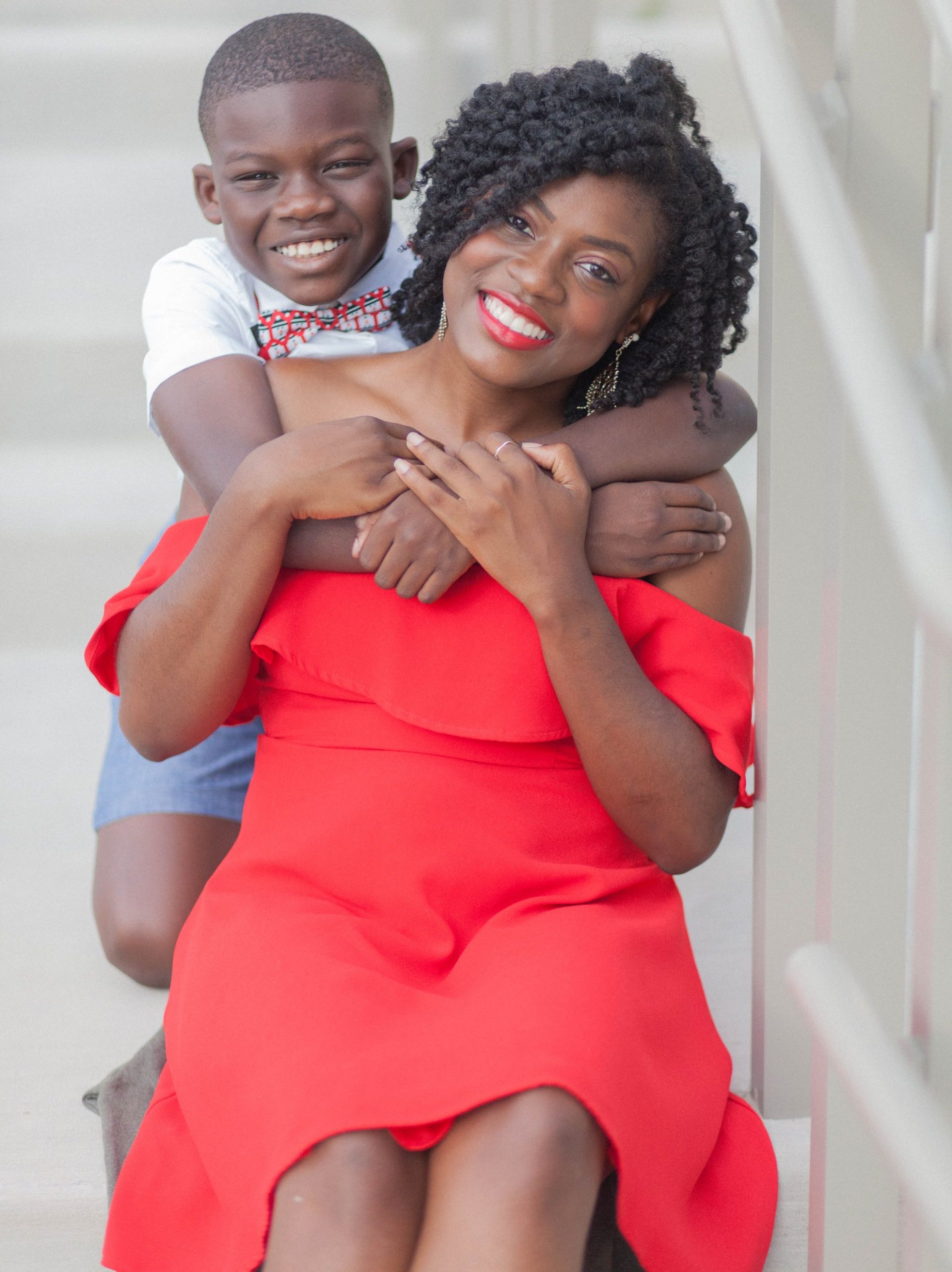 young boy hugging mother in red dress