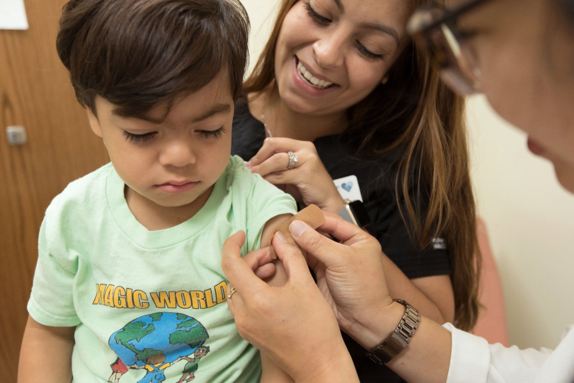 doctor applies bandage after vaccinating young boy