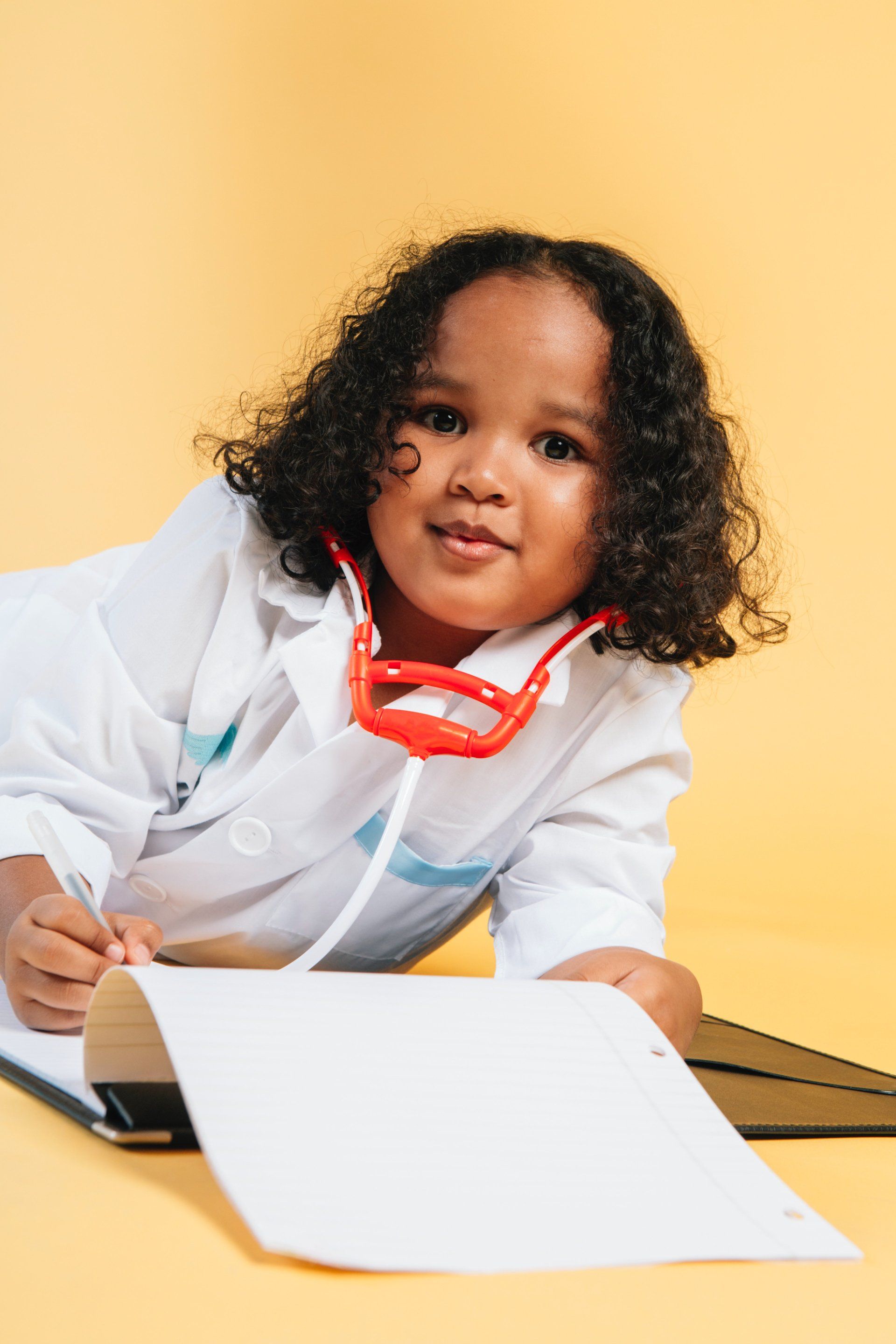 young girl playing doctor on yellow background