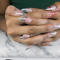 Hands with long silver acrylic nails crossed on a marble surface.