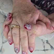 Two hands showing red and pink manicured nails, one hand wearing a gold ring.